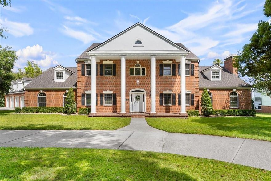 Winter Haven Chain-of-Lakes Executive Home on 1.86 Acres with Lake Eloise Frontage! Welcome to this elegant two-story home nestled on nearly 2 acres in a serene, park-like setting on Lake Eloise. From the moment you step into the grand foyer—with its sweeping curved oak staircase, wainscoting, and a stunning Palladian window—you'll appreciate the timeless craftsmanship throughout. The spacious living room centers around a large fireplace with a custom-designed Georgian mantel and matching built-in bookcases. In the formal dining room, you’ll find exquisite built-in cabinets, while the private library features rich, custom cherry wood bookcases. The gourmet kitchen is a chef’s dream, complete with a Jenn-Air double ovens, built-in breadbox, appliance garage, and cutting boards—all seamlessly integrated. The kitchen and breakfast area with an expansive 15x31 feet of space, ideal for both cooking and entertaining.  Additional features include insulated Anderson casement windows, a dramatic two-story Greek Revival front portico, and wide 4-foot hallways throughout. Thoughtful details such as keystone window headers, dentil molding under the eaves, and decorative quoins on the brick front elevation add architectural charm.  Enjoy your heated Infinity saltwater Pool with stunning views of the shaded backyard and Lake Eloise.  Practical touches abound, including an underground dog fence, irrigation system, deep well with water conditioning, dual hot water heaters (including one with a heat recovery unit), and a dual-zone A/C system.  The interior also boasts a well-equipped laundry room with cabinets, a built-in ironing board, and a laundry chute. Storage is plentiful, with easily accessible closets and attic spaces. Architectural features continue indoors with transom windows above the archways in the dining and living rooms, and a beautiful sunburst elliptical window with sidelights welcoming guests at the front door.