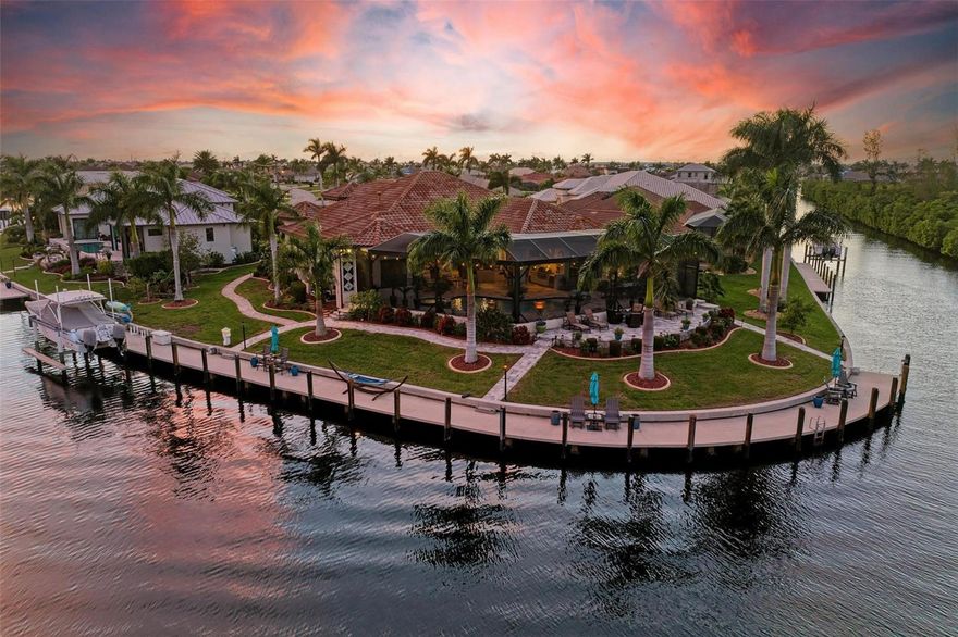 INCREDIBLE 4 Bedroom/3 Bathroom + office, 3 Car Garage CUSTOM POOL HOME with GENERATOR & FULL HURRICANE PROTECTION, ON TIP LOT with 190 FEET OF NEW CONCRETE SEAWALL/DOCK with 10,000# LIFT & FAST, DEEP-WATER ACCESS to Charlotte Harbor & the Gulf of Mexico awaits new owners!  This Arthur Rutenberg masterpiece was designed with every detail in mind, so be sure to ask for the full FEATURES SHEET.  From the outside, enjoy newly sealed concrete pavers in the driveway and all sidewalks, along with exterior pathway lighting and upgraded landscaping throughout. At the entry/front porch, enjoy custom double doors with a hurricane rolldown shutter and separate screen feature to let breezes pass through.  Inside, find a magnificent view from every space in the house with incredible privacy due to the oversized tip lot on the RIM CANAL with no neighbors behind.  From the foyer, the office is to the right with a coffered ceiling, plantation shutters, & bay windows.  To the left is the formal dining room w/ beautiful built-in details, plantation shutters, & a bar area, convenient for both this space and the great room.  Farther in, find yourself captivated by the incredible living spaces, all with sealed Travertine floors and inlaid engineered hardwood details.  The great room has a large feature wall w/ a gas fireplace & mantle w/ under cabinet lighting, coffered ceilings & a wall of sliding glass doors to connect the outside entertaining space.  The gourmet kitchen is open to the great room & dinette area, with a dual tier granite breakfast bar/island, a separate coffee bar area with cabinet front icemaker, upgraded appliances including a 6-burner propane gas cooktop & hood, built in ovens, under cabinet lighting, & a water treatment system in the kitchen.  The dinette area w/ aquarium glass is the perfect spot for your morning coffee, as you watch the sunrise over the pool and long water view of the canal, too!  Off the kitchen towards the street, find 2 separate walk-in pantries, a large laundry room with extra cabinets/sink & storage, a drop zone area that connects to the 3-car garage with electric screen system for enjoying the breeze through the home, and tons of extra storage. On the other side of the kitchen find a guest bathroom and 2 spacious guest bedrooms & a 4th bedroom that is oversized & overlooks the pool area with electric shades, currently used as an office/studio.  On the opposite side of the home, find a spacious primary bedroom w/ dual walk-in closets w/ organizers, a spacious bedroom w/ bay window sitting area & tray ceilings, private access to the lanai, roman shades and privacy electric blinds & plantation shutters for comfort, and an en-suite bathroom w/ a large shower w/ glass wall, dual vanities, a linen cabinet, & private toilet room.  On the lanai, enjoy travertine pavers throughout, with ample entertaining spaces, a full outdoor kitchen, outdoor shower, a lighted water bowl features spilling into the pool and an oversized pool and spa enclosed by an over-engineered NEW pool cage w/ panoramic window.  Farther outside find a separate patio area overlooking the water, 3 walkways to the dock, lighting, a private raised garden, and extra storage for fishing poles/pool items.  Enjoy relaxing at the water's edge on the dock or hop on your boat in your backyard with a quick ride out via Buckley's Pass to the harbor.  This home has it all and is ready for you!  Schedule your showing today!