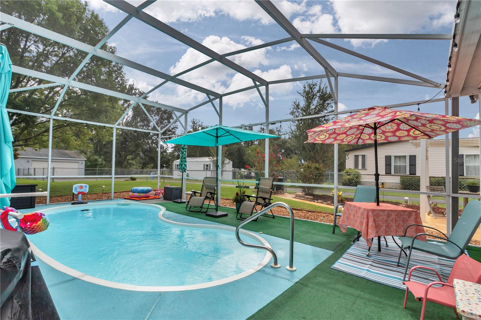 YES, YOU CAN HAVE IT ALL! Outstanding upgraded manufactured pool home in the Oakland Hills neighborhood where you OWN THE LAND and have NO HOA. A must see, 4/2 split bedroom home with in-ground pool and birdcage, enclosed lanai and detached 2 car garage with workshop and utility shed! Enjoy this well maintained, almost 2000 sq. ft. home, which includes a fully fenced rear yard on a .63 acres lot, with no rear neighbors and beautiful landscaping. The inviting FRONT PATIO is a great place to enjoy your morning coffee or afternoon sunsets. As you walk in, you are greeted with a large and bright living room, vaulted ceilings and a WOOD BURNING FIREPLACE. You continue through into a lovely dining room area set near the home’s heart, the LARGE OPEN KITCHEN adjoined with an equally large FAMILY ROOM/SECOND LIVING SPACE, great for families and entertaining. The kitchen includes ample counters (refinished in 2024) and abundant cabinet space. In addition to your Samsung electric range, there is an ADDITIONAL BUILT-IN OVEN for all of your holiday and hosting needs. The home’s split plan includes a large primary bedroom with WALKTHROUGH CLOSET (custom built-in system), large renovated en-suite bathroom (2024), with a CAMBRIA QUARTZ double sink vanity, glass enclosed shower and newly resurfaced garden tub. Back across the home, you will find the 3 bedrooms and 1 updated bathroom (matching cambria quartz). Just before entering the indoor laundry room, there is a BUILT-IN OFFICE NOOK with more storage cabinets and shelving, perfect for those remote jobs or school work. As you head out back to the SPACIOUS OUTDOOR RETREAT, you enter the enclosed lanai (all vinyl windows replaced in 2021), to enjoy the incredible view of the shaded yard, maintained oak trees and small fire pit. Continue through into a BIRD CAGE with a wonderful IN-GROUND POOL, which has new (June 2025) Pool Pump and Filter systems, and includes a robotic pool cleaner. At the end of the paved property-length driveway, you come to the DETACHED 2 CAR GARAGE (20ft wide x 23.25ft in depth) with a BONUS ATTACHED WORKSHOP (an additional 9.5 ft wide with the same depth), including ATTIC STORAGE, complete with pull down ladder access. To top it off, property includes an additional UTILITY SHED for all your outside tools and equipment! (Ask about the negotiable Husqvarna riding lawn mower.) Additional upgrades include: A/C 2016, Drain Field 2018, UV window film 2019, and Water Heater 2020. This neighborhood is QUIET AND PEACEFUL, almost rural, while being within 5 minutes of all your needs including The Villages Spanish Springs entertainment square, all of your shopping needs (US-441), and in range of many quality schools! CALL TODAY TO SCHEDULE YOUR SHOWING!