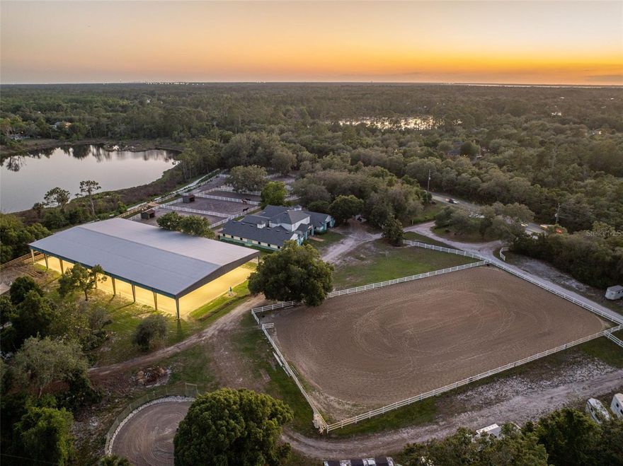 Tucked beneath majestic oak canopies and surrounded by the beauty of Old Florida, welcome to Silver Springs Equestrian,a rare opportunity to own an established, income-producing equestrian facility in the heart of Geneva. Situated on 10 gated acres with peaceful lake views and endless possibilities, this exceptional property blends functionality, charm, and true equestrian lifestyle living.  Designed as a full-service community equine facility, Silver Springs Equestrian offers boarding, training, lessons, trail rides, clinics, and space for both local riders and traveling equestrians alike. The grounds are thoughtfully laid out with 23 stalls between two wide aisle barns, 15 paddocks, multiple riding and training areas, and impressive infrastructure already in place for a thriving operation or private estate.  
Equestrian amenities include a 100’ x 200’ covered and lighted arena with upgraded footing, a 200’ x 400’ outdoor arena complete with jumps, standards, barrels, poles, and dressage setup, plus a 60’ round pen for training and exercise. Additional features include hot and cold water wash racks, grooming and tack-up bays, gated entry, extensive parking inside and outside the gate, and three 50-amp RV hookups with water service. Whether you envision a premier boarding and training facility, private horse farm, clinic destination, or family compound, this property is equipped to deliver.  The primary residence offers a unique and functional layout with living quarters thoughtfully integrated into the equestrian lifestyle. Upstairs features two bedrooms and a full bath, while the lower level includes an office, oversized tack room with sitting area, laundry room, and additional half bath. A separate 3 bedroom, 2 bath secondary residence provides ideal accommodations for guests, trainers, staff, rental income, or multi-generational living.  Perfectly positioned approximately 1.5 hours from the World Equestrian Center, under an hour to Orlando attractions, and within reach of Florida beaches, this one-of-a-kind Geneva equestrian estate combines peaceful country living with convenience and opportunity. From the sprawling oak-lined grounds to the fully equipped training facilities, Silver Springs Equestrian is more than a property.....it is a destination and lifestyle.