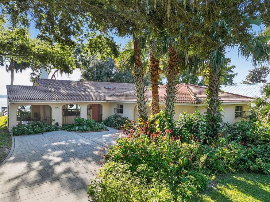 Welcome to this charming lakefront retreat on the shores of Lake Dora—offering timeless cottage-style character, stunning water views, and an unbeatable location along the Harris Chain of Lakes. Nestled on a spacious lot with mature shade trees, and landscaping, this beautifully maintained home blends relaxed Florida living with DIRECT LAKE FRONTAGE and inviting indoor–outdoor spaces.
Step inside to an open, light-filled layout featuring warm finishes, generous windows, and views that frame the sparkling lake from multiple rooms. The kitchen offers tile floors, ample cabinetry, breakfast bar and flows seamlessly into the dining area and overlooks the living room with wood burning fireplace. Just off the kitchen is a side screened porch perfect for morning coffee, sunset watching, or breezy gatherings.
The family room has sliding doors with hurricane shutters and opens directly to the expansive backyard patio overlooking the tranquil backyard and water. There is also a cozy Florida Room with beautiful lake views. 
The primary suite provides comfort and privacy with an en suite bath and walk in closet, while guest rooms & guest bathroom is ideally positioned for family or visitors. 
Outdoor living shines here, with 80+ feet of direct, private lake frontage, seawall, boat dock with electric and water. 
Lake Dora is ideal for boating, kayaking, fishing, or simply enjoying life on the Chain. Whether you envision weekend escapes or full-time waterfront living, this home offers a rare opportunity to own an idyllic piece of Tavares’ most desirable waterfront. Other features are concrete block construction, barrel tile roof, side entry 2 car garage and new well and filtration system 2025. Located in the county with no city taxes and equipped with irrigation from the lake, well and septic, this property offers valuable ongoing savings and lower monthly expenses.
With no HOA and proximity to downtown Mount Dora and Tavares’ waterfront entertainment district, boutiques and restaurants lake recreation is endless right from your backyard! This property delivers the best of Central Florida lake life.