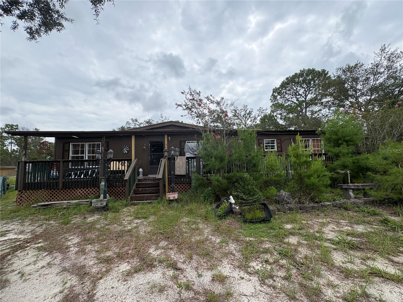 Tucked away on nearly 5 acres of fully fenced land, this charming 3-bedroom, 2-bathroom manufactured home offers the perfect blend of rustic character and modern comfort. Ideal for those seeking privacy, space, and the freedom of agricultural zoning, the property is thoughtfully designed for both relaxation and functionality. Inside, the spacious 22x16 living room features cathedral ceilings, durable laminate flooring, and a cozy corner wood-burning stove with stone accents. Just off the living area, the 15x13 dining room provides an inviting space for entertaining, complete with matching finishes and elegant French doors that lead into the kitchen. The kitchen itself is full of personality, boasting custom rustic cabinetry, a dual oven stainless steel appliance package, decorative tile backsplash, and stone-finished flooring. A separate 11x11 breakfast nook with shiplap accent wall adds to the charm while offering access to the 19x10 covered side porch. The nook also houses a convenient laundry closet with washer and dryer hookups.
The home’s split floor plan provides ultimate privacy. The primary suite measures 14x13 and includes dual closets and a beautifully styled en-suite bathroom with dual sinks, stone detailing, a relaxing garden tub, and a tiled walk-in shower. Both secondary bedrooms offer generous walk-in closets—bedroom two measures 13x12, while bedroom three is 12x10—and they share a guest bathroom featuring wainscoted walls, chair rail molding, corrugated metal paneling, and stone-accented finishes around the tub/shower combo.
Outside, this property is a true rural retreat. A 64-foot front porch wraps toward a welcoming side entry, while the rear of the home features a 12x12 open porch and a paver patio ideal for outdoor gatherings or peaceful evenings. Animal lovers will appreciate the sectioned dog runs with AC-cooled dog housing, a detached 2-car carport, multiple storage sheds, and a horse barn with stalls. With plenty of room to grow, explore, and enjoy the outdoors—including a designated burn pit—this property is a rare opportunity to live the lifestyle you've been dreaming of, all just a short drive from town amenities.
Opportunities like this don’t come around often—schedule your private tour today and discover the freedom, functionality, and charm this unique homestead has to offer. Your dream of country living starts here!