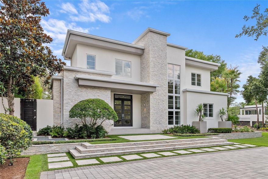 Award-winning Phil Kean design on a prominent corner lot in the heart of Winter Park, just minutes from Baldwin Park, Park Avenue, and East End Market—home to Michelin-rated dining and upscale retail. This 5-bed, 5.5-bath residence delivers clean lines, smart design, and seamless indoor-outdoor flow. Recognized with multiple honors, including the 2015 Parade of Homes 1st Place Award for Custom Homes, the American Residential Design Award from the AIBD, and the prestigious 2015 Aurora Awards, this home reflects the highest level of architectural achievement. A retractable Nanowall opens to a private outdoor escape with a heated saltwater pool, summer kitchen, fireplace, motorized screens, and mature bamboo landscape. Two driveways and a freshly laid zoysia lawn add presence to the front approach. Inside, 10’ ceilings and a fluid open plan frame the chef’s kitchen—finished with waterfall quartz, touch-close cabinetry, and Thermador appliances including a steam oven, induction cooktop, and 98-bottle wine cooler. The media room includes surround sound, a motorized screen, and a second retractable wall to the pool. Smart home controls manage lighting, security, Sonos, and cameras with ease. The guest suite offers a Murphy bed and private bath. The primary features a fireplace, spa-style bath, and custom closet. All bedrooms include en-suite baths. Additional highlights: whole-house generator, water filtration, foam insulation, sweep-in vacuum, and an EV-ready garage with custom storage.