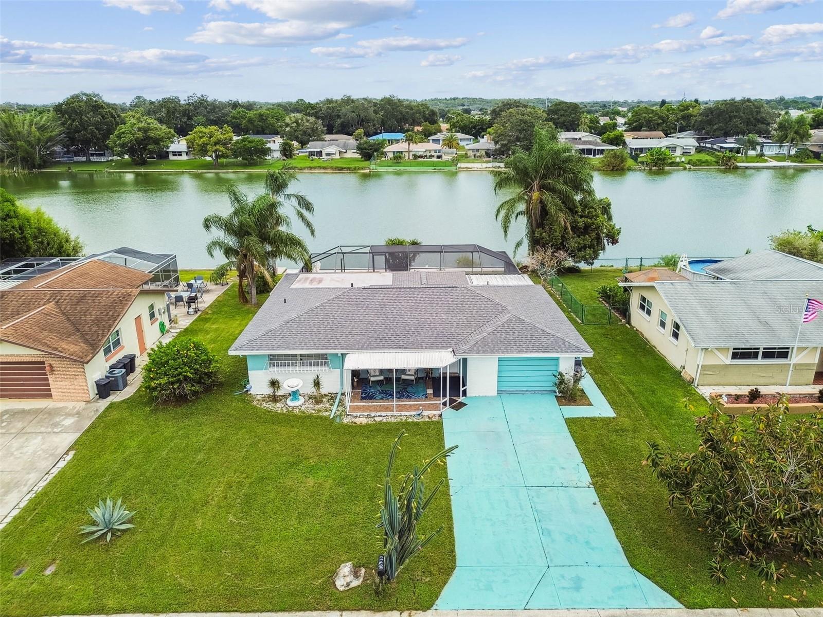 Discover the perfect blend of comfort and Florida lifestyle in this spacious 3 bedroom, 2 bath pool home with stunning lake views. Nestled on a quiet street, this property offers a welcoming front porch, double parking, and a beautifully landscaped yard. Inside, enjoy a bright family room with large windows, a versatile dining area, and tile flooring throughout. The oversized primary suite features a generous closet and a retro inspired en suite bath with classic blue and white tile. A large kitchen with a pass through window to the porch makes entertaining effortless. Multiple living areas including a Florida room and a flexible family room with sliders create endless possibilities for relaxing or hosting guests. Step outside to your private oasis: a covered patio, sparkling pool with mosaic details, and tranquil lake views perfect for paddleboarding or simply unwinding. With three spacious bedrooms, ample storage, and an indoor laundry area, this home has it all inside and out. (ROOF-2021)(W/H-2020)(A/C-2012)(REPAIRED SINKHOLE-2008)