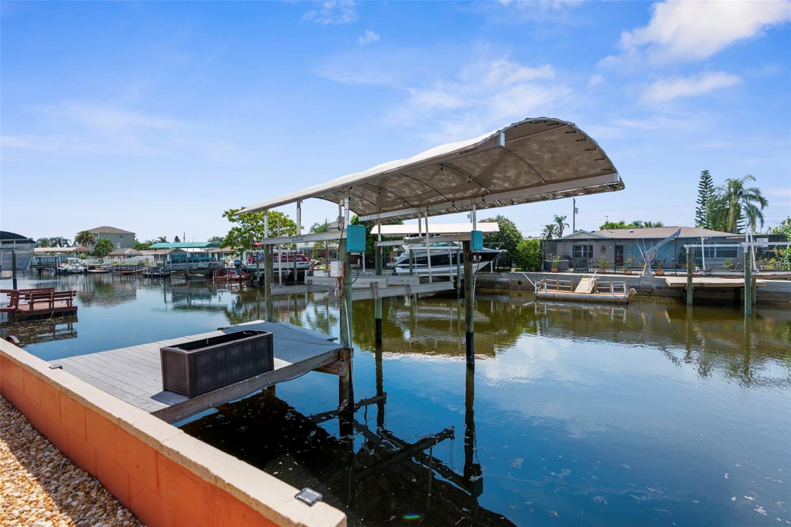 Assummable FHA mortgage-3.25% Interest rate with about a $300,000 loan balance!!! New seawall 2016, AC and waterheater
2024, roof 2019, flat roof 2021. This coastal home has been completely remodeled, but the real star of the show is the bonus
Florida room and backyard. You'll find most of your days and evenings in the AC watching the water views in the Florida room, or
outside at your bar top. Your weekends can be spent on the boat with about 15 min idle time to the Gulf. Your boat will be protected
from the sun with the lift cover as a bonus. This home has plenty of parking between the car port, garage and addition parking pads.
No need to worry about lawn maintenance, this house only has a few landscape beds and plenty of self maintaining palm trees,
adding to the tropical vibe you are looking for. Stepping inside this beautifully renovated home, your notice the quartz countertops in
the kitchen, upgraded light fixtures and a line of sight to the water from the front door. This home offers ample storage solutions
from the indoor laundry closet to the walk in pantry/closet. Bring your boat and your golf cart and enjoy sunsets from your backyard,
or take the golf cart to one of the neighborhood restaurants at Hudson Beach!