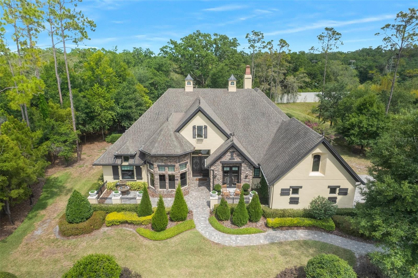 Welcome to your DREAM HOME!! Come fall in love with this elegant home from the French Country collection Built by Adobe featuring ample living space, open-concept floorplan, and unique architectural elements. This luxurious 5-bedroom, 4.5 bathroom, oversized side entry 3- car garage, pool home provides a much-needed retreat from today’s hectic lifestyle. Perfectly situated on a gorgeous 1.03 acre lot in the sought after and gated Pine Cove Estates in Odessa FL! Everything about the exterior design will catch your attention- details are inspired by romantic European country architecture and paint a timeless scene of the French countryside. Rooflines with steep peaks and slopes are adorned with decorative finials, cupolas and authentic copper chimney caps. Radiating front courtyard is defined by low walls, lush landscaping, brick pavers, flowing water fountain, and trellis garden, offer an instant warm welcome to all. Hanging lanterns, wood-slatted shutters, recessed arched windows, and gorgeous front entry double doors add the finishing touches of charm. Once inside you’ll notice the interior elements inspired by the works of old-world carpenters. The grandeur front foyer will lead you to the formal living/dining room detailed with 16-foot ceilings, crown molding, exposed beam work, romantic fireplace, and decorative hanging chandeliers. The Chef’s worthy Gourmet Designer kitchen is PERFECT for entertaining and features 42” custom cabinetry with crown molding, dovetail soft-close drawers, and a stunning custom range that perfectly sits above a brushed nickel pot filler faucet, and a 6-burner gas stove cook top! Other kitchen features include: granite countertops, farmhouse sink, travertine stone backsplash, walk-in pantry, built-in double wall ovens, trash compactor, matching high-end stainless-steel appliances, wine fridge, and an extra-large center island! In the main living areas, you will discover premium engineered wood flooring and classic modern baseboards. The expansive Primary Suite boasts tray ceilings, grand fireplace, oversized his and her walk-in closets complete with custom built-in closet organization systems. The gracefully appointed primary ensuite features dual vanities, granite countertops, dropdown chandelier lighting, warm water bidet, oversized spa-like shower, and a beautiful free standing garden tub. Triple French doors provide access to the stunning resort style oasis pool area. Complete with an outdoor kitchen, dim lighting, tongue & groove ceiling, and a panoramic screen enclosure which provides very peaceful, tranquil, unobstructed views of the backyard. Relax or entertain in the crystal-clear saltwater pool, heated waterfall spa or near the freestanding, outdoor fireplace. Additional home features include: 500-gallon propane tank for the whole house generator, Hurricane impact windows, and hurricane motorized rolling shutters off the lanai help to protect your home from all of the elements. The local residents are just as amazing – while striving to keep the last of the Odessa/Keystone rural communities intact by supporting the surrounding wildlife sanctuaries, Agriculture businesses, farming, lakes for fishing & living, and all that encompasses this unique paradise. Pine Cove Estates is a private, tucked away community with 11 1-Acre lots. Conveniently located near great shopping, schools, and restaurants! Only 5 minutes from the Suncoast Parkway & Trail, and only 25 minutes from Tampa International Airport.