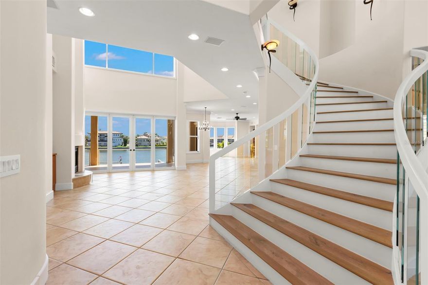 Welcome to a stunning custom waterfront home in the prestigious Kipps Colony within Pasadena Yacht & Country Club. This well built transitional modern masterpiece offers luxury living on deep, protected water just minutes from the Gulf. A circular drive leads to a spacious four-car + garage, with an elevator providing easy access to all levels. The grand foyer opens to formal dining and living rooms with cathedral ceilings and elegant glass railings. The first level of this 5287 SF home includes a waterfront office/bedroom, a media room (5th Bedroom), and a gourmet kitchen with custom cabinetry, granite counters, and top-of-the-line appliances. The master retreat features a morning kitchen, sitting area, waterfront balcony, and a lavish bath with dual sinks and separate soaking tub and shower. Two additional bedrooms with en-suite baths complete the upper level. Breathtaking stained glass windows highlight the front of the home, high ceilings, and expansive glass showcase stunning water views. Outdoor living includes expansive waterfront balconies, an elevated spa spilling over into the pool, a cabana room, and a dock with 16,000 boat lift, perfect for enjoying the sparkling waterway. Offering almost 8000SF under roof and 5 bedrooms, 4 1/2 baths, this home offers something for every member of the family. Experience unparalleled luxury and sophistication in this magnificent home in Pasadena Yacht & Country Club, Pinellas County's only gated, golf course and waterfront community on Boca Ciega Bay. This exclusive club offers fine and casual dining, fitness, personal training, a waterfront heated lap pool, tennis, pickleball, a marina & more. The buyer of this home has the ability to skip the lengthy wait lists and join the club upon purchase. You truly can have it all!