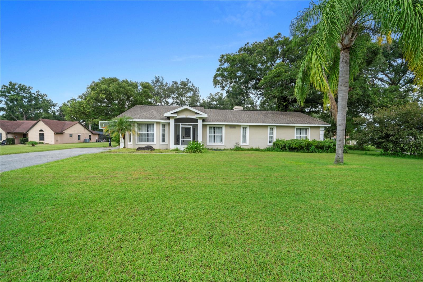 Short Sale. Nestled on a generous 1.2 acre canvas lies a custom-built sanctuary that harmonizes space, grace, and possibility. At approximately 3,488 sq ft, this single-story home (built in 2000) offers both elegance and practicality. A screened front alcove welcomes you inside, where a sunlit family room unfolds, boasting tray or coffered ceilings, a cozy fireplace, and sweeping 24-inch ceramic tile flooring that glides through the communal spaces. The heart of the home—the kitchen—is artfully updated with granite countertops, stainless-steel appliances, crown molding, and contemporary lighting. It connects seamlessly to a breakfast nook framed by a bay window, a formal dining zone, and an endearing coffee bar illuminated by natural light. Designed for the rhythms of a modern multi-generational family, the home features 5–6 bedrooms across three distinct living wings. On one side, four secondary bedrooms are paired through Jack-and-Jill bathrooms. On the opposite side lies a serene master retreat, your private haven with a luxurious bathroom outfitted with a dual-nozzle shower, a separate soaking tub, dual vanities, and high-end finishes that evoke a spa-like serenity. Perhaps this home’s most versatile asset is the in-law (or guest) suite—a self-contained haven complete with a private entrance, kitchenette, full bath, and flexible living space. Ideal as a studio, home office, guest quarters, or income-generating rental. Step outside to explore nearly half an acre of possibilities—a screened patio leads to an open-air patio ripe for BBQs and lounging.