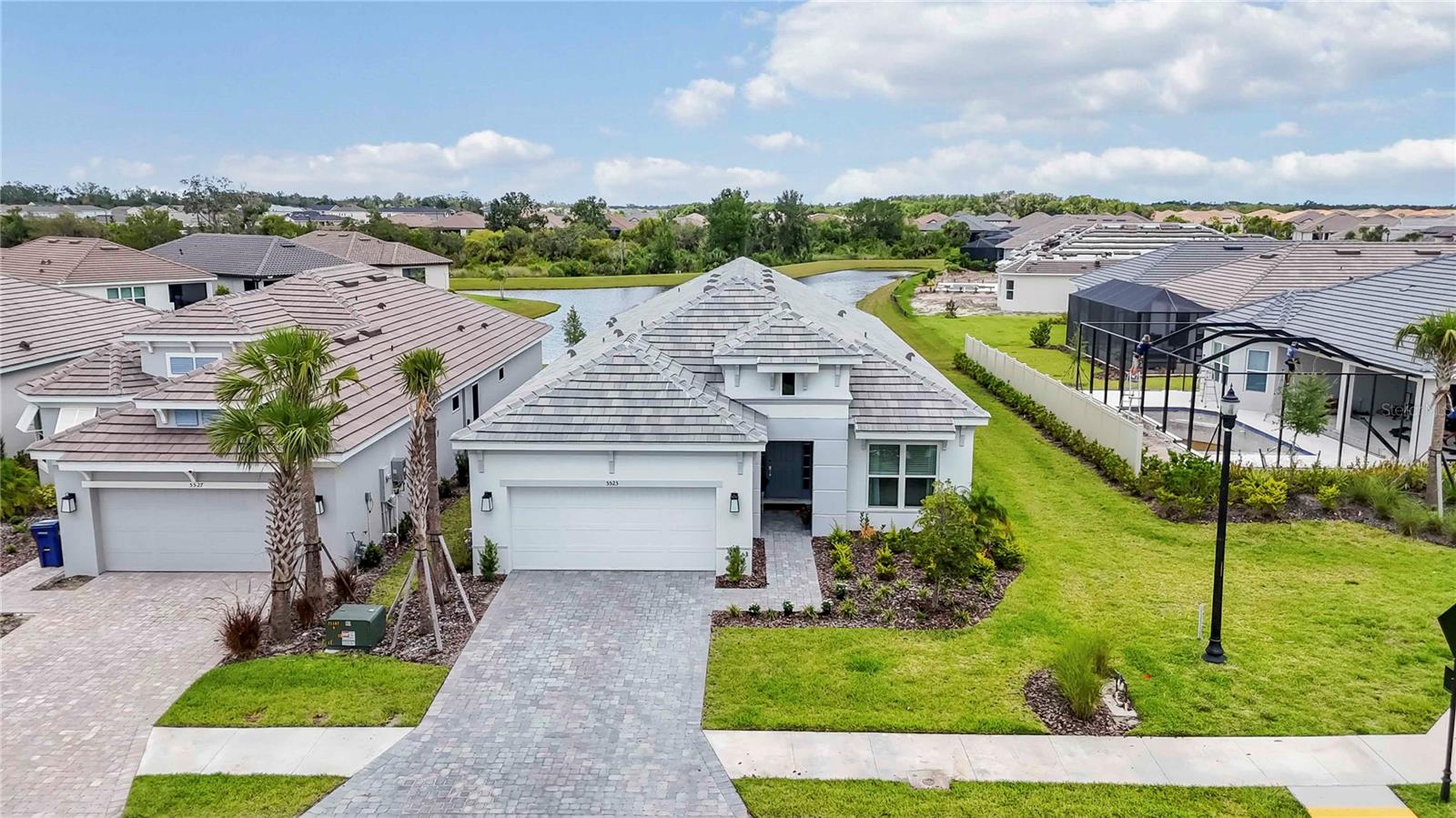 Welcome to Your Dream Lakeview Retreat Located at 5523 Orwell Street in the prestigious Artisan Lakes Esplanade—a resort-style, maintenance-free gated community in Palmetto, FL—this exquisite home offers the ultimate in luxury living. Nestled on a premium lakefront lot, the largest Lazio floor plan available this nearly brand-new 8 month old residence captures breathtaking sunset water views and is ideally situated just steps from the brand-new amenity center resort pool. Outdoor Living at Its Finest the extended lanai is an entertainer’s dream, featuring two designer ceiling fans, an outdoor kitchen hookup, and panoramic views of the tranquil lake and protected conservation area. The expansive lot offers ample space for a custom pool and spa, with professional quotes available from top-rated builders.
Elegant Interior Features Step inside to a stunning open-concept floor plan with soaring 10' ceilings, elegant tray accents, and 8' doors throughout. This meticulously designed home boasts: 3 Bedrooms + Den/Office, 3 Full Bathrooms Luxury wood-look plank tile flooring for effortless maintenance. Two sets of sliding glass doors, flooding the living areas with natural light
Pocket french doors for the Den/office and the pocket door separator for the front bedroom & bathroom for optimal guest privacy.
Chef’s Gourmet Kitchen?A culinary masterpiece awaits with: 42” upper cabinets, Quartz countertops, Stainless steel appliances, Farmhouse sink + prep island sink, Gas cooktop for precision cooking. Serene Primary Suite, Relax in your luxurious primary bedroom with upgraded bay windows framing the serene lake view. The spa-inspired bathroom features an oversized glass-enclosed walk-in shower and dual vanities. A generously sized walk-in closet offers plenty of space and storage. Smart Storage & Garage Solutions Enjoy a well-appointed laundry room with utility sink and cabinetry. The extended 2-car garage comes complete with 3 newly installed ceiling-mounted storage racks for a clean, clutter-free lifestyle. Hurricane Shutters Included. Live the Esplanade Lifestyle From lush landscaping and scenic lakes to high-end amenities and a vibrant social calendar, Artisan Lakes Esplanade offers a lifestyle like no other—designed for those who appreciate elegance, comfort, and convenience. With easy access to I-75, you're just a short drive from the Gulf of Mexico beaches, shopping, dining, and Tampa, St. Petersburg, Bradenton, and Sarasota. Experience the perfect blend of luxury and location in this pet-friendly oasis. Living in the HOA maintained community, Artisan Lakes at Esplanade means indulging in an array of amenities, including a state-of-the-art fitness center, tennis courts, pickleball courts, bocce ball, a resort-style pool with cabanas, a hot tub, and a resistance pool. Nature lovers will appreciate the walking trails, dog parks, playground, and butterfly garden. The HOA provides cable TV, internet service, and yard maintenance, ensuring a convenient and enjoyable living experience. No evacuation zone, No flood insurance required, 40 feet elevation. 2 large pools, lap swim lanes, spa, resistance pool, pickleball, tennis, bocce, shuffleboard, full fitness enter, lots of classes, clubs and events for all interests. Enjoy the best of Florida living and schedule your showing today to make this exquisite home yours. Don't miss out on the chance to immerse yourself in the resort-style living offered by the at Artisan Lakes of Esplanade
