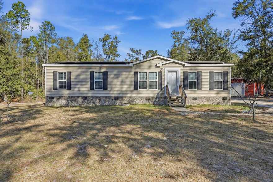 Embrace the ultimate "Spring Life" on this peaceful 10-acre retreat, located just minutes from the world-famous Ichetucknee River! Nestled on a private lot, this energy-efficient 4-bed, 2-bath manufactured home is move-in ready and features solar panels, as well as texturally rich elements, a spacious open-concept layout, and a split-bedroom plan for maximum privacy. Stepping indoors you will find a living room that flows effortlessly into the beautiful dining area and island kitchen boasting additional seating, a newer appliance package, and access to the large laundry room, complete with washer and dryer. Off the living room, you will find the primary suite featuring a walk-in closet and ensuite bath with double vanities, tub, and walk-in shower. Across the home are three generous guest bedrooms and a full guest bath with a tub/shower combo. Step outside onto 10 sprawling acres where your imagination can truly run wild. This expansive property offers the ultimate blank canvas to fulfill your country-living desires—whether you dream of a private mini-farm, a sparkling swimming pool, or a massive homestead garden. You’ll find 2 functional sheds already in place, perfect for storage, creative hobbies, or a dedicated workshop. With no shortage of space, there is plenty of room for your RV and boat storage, or even a custom outdoor entertainment oasis. Located in the heart of Fort White, this home offers a true "Old Florida" lifestyle defined by quiet nights and world-class outdoor recreation. Fort White is a close-knit community where life moves at a slower pace. You won't find big-box stores or heavy traffic here; instead, you’ll find local diners, a public library, and neighbors who know each other. Known as the "Home of the Ichetucknee River," this area is a world-class hub for tubing, kayaking, and cave diving. While the setting is rural, it is far from isolated; positioned almost exactly halfway between Lake City and Gainesville, it is the perfect spot for those seeking privacy without sacrificing a manageable commute. This property is just 5 miles from the town center, 10 miles from Ichetucknee State Park, and a short, scenic drive to the fresh water springs and boutique shops of High Springs. Whether you’re looking for a full-time residence or a weekend getaway, this eco-conscious property is a rare find in a high-demand area. Schedule your private tour today and start living the Florida lifestyle!