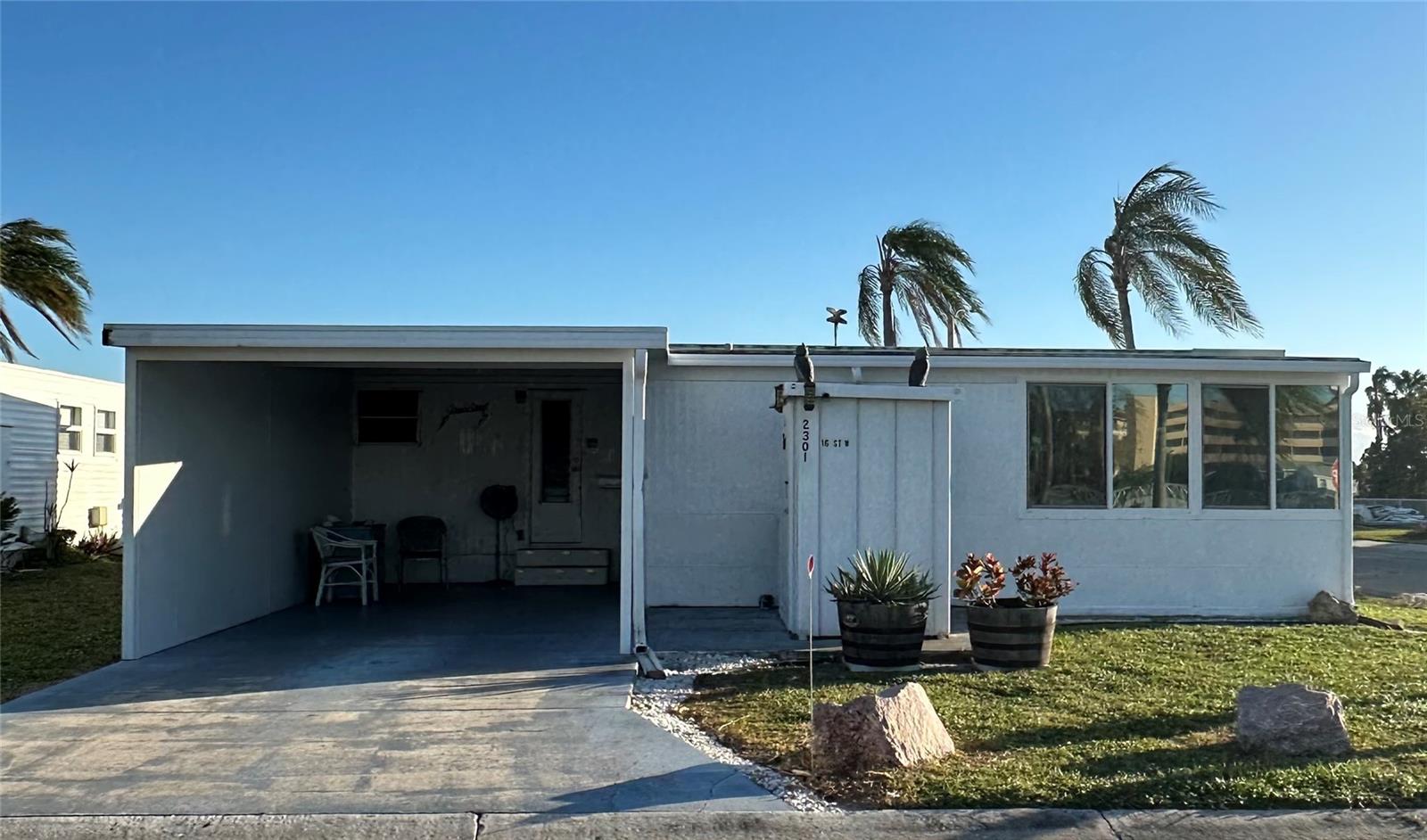 Charming home comes fully furnished, boasting a host of great features such as a new moisture barrier and tie-downs installed in 2017, updated plumbing, and a roof-over with a lifetime transferable warranty from the same year. The property has been treated for termites and maintained with quarterly pest service since. Privacy is enhanced by a newly added aluminum wall to the carport in 2022. The home features a generous lanai, outfitted with glass sliding windows and 3M tint to minimize sun glare, ensuring a comfortable and secluded space. The lanai is roomy enough to function as a family or recreation room and can also accommodate guests. Nestled within the secure confines of Bradenton Tropical Palms, it's a stone's throw from the main gate and the plethora of amenities offered: a 60 x 40 heated pool, a professional fitness center, a library/activity hub, a large meeting hall with seating for 300 and a grand stage, 22 shuffleboard courts with a community league, indoor air-conditioned pickleball courts, a gazebo, a memorial garden, and meticulously groomed walkways. Bradenton Tropical Palms is conveniently located near Lecom Park, home to the Pittsburgh Pirates, a variety of nature preserves, and over 35 golf courses within a 15-mile radius, not to mention its proximity to the airport. Visit this home and community today and see for yourself!