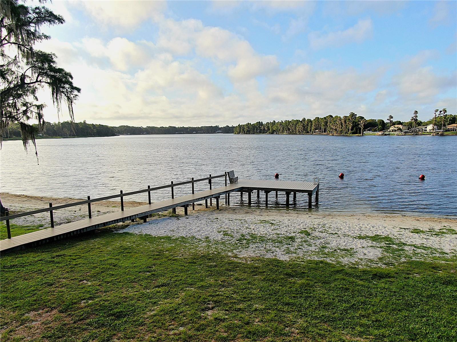 Discover Your Dream WATERFRONT PROPERTY on a CHAIN of 3 SKI SIZED LAKES
Welcome to an unparalleled opportunity to own a piece of paradise in a gated community that offers the finest in lakefront living. This large, waterfront lot is nestled in a park like community on not one, but three ski sized connected lakes, creating an aquatic haven for water sports enthusiasts and nature lovers alike. A perfect place for boating, water skiing, fishing, and kayaking. The property already includes a covered dock, well, septic tank, and drain fields.
This unique community designed for relaxation and recreation. Residents enjoy a private beach area complete with a boat ramp, Multiple docks, grills, picnic tables, sand volleyball court, horseshoes, and a designated swimming area. Whether you’re looking to spend a lazy afternoon basking in the sun or hosting a lively barbecue, this private beach area has it all.
Children will delight in the community playground, featuring a basketball court and ample space for play. The entire community is golf cart friendly, allowing for a leisurely ride through the picturesque surroundings, especially to the beach area and other amenity areas as well.
This idyllic community is dotted with majestic oak and cypress trees, creating a park-like atmosphere that invites you to connect with nature. As
you meander through the tree-lined streets, you'll appreciate the tranquility and beauty that defines this unique locale. The gated entrance ensures privacy and security, giving you peace of mind as you enjoy the numerous amenities.
One of the standout features of this property is that all impact fees have already been paid, streamlining the building process and saving you time and money.
Whether you’re an avid boater, a fishing enthusiast, or simply someone who enjoys an active lifestyle, this community caters to all your recreational needs. The lakes are perfect for skiing, fishing, & kayaking, while the community spaces provide endless opportunities for outdoor fun. The convenience of the private boat ramp and fishing dock means you can easily indulge in your favorite water activities.
This community fosters a welcoming and vibrant atmosphere. Neighbors become friends at the beach area, children play together at the playground, and families gather for barbecues and picnics. The golf cart-friendly design encourages a sense of camaraderie as residents explore the community and enjoy the natural beauty together.
With its prime location on a three ski-sized lakes, this property is ready for you to build your dream home. Experience the lifestyle you’ve always envisioned—where every day feels like a vacation.
Schedule to see this property today