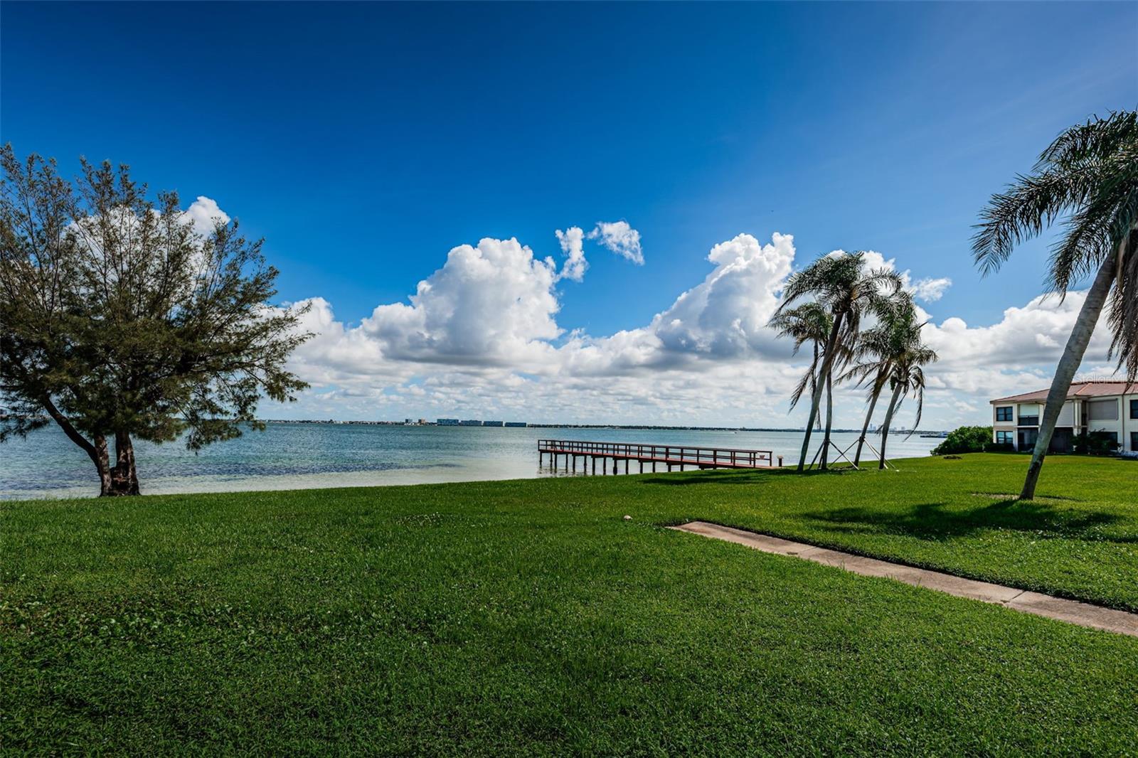 Tranquil views from this 2-bedroom 2-bathroom condo which is perfect as a permanent home or a seasonal getaway! Step in and immediately notice the gorgeous view of Boca Ciega Bay and picturesque fishing pier. The kitchen is a great place to prepare food and serve guests which features hardwood birch cabinetry, recessed lighting, ample storage with workspace. and classic crown molding. In the living area you’ll find a generous sized space to entertain while enjoying the gorgeous views. The primary bedroom has a large walk-in closet and an ensuite bathroom with updated vanity and fixtures. The secondary bedroom and updated bathroom with step-in shower are separated by a pocket door providing additional privacy. This bedroom has a perfect view of the bay with access to the patio. Despite being a ground floor unit, the unit had no water intrusion from 2024’s hurricane season. Know your investment has been well maintained, as it features a 2019 AC unit and a 2024 water heater and updated windows. Assigned under building parking #44 only a few steps from the front door. Take advantage of a golf, tennis, yacht or social membership offered at Isla Del Sol Yacht & Country Club. All of this, and within minutes of the award-winning beaches of Fort Desoto State Park, and top ranked St Pete Beach. Or with easy access to I275, you're only 15 minutes to the vibrant activity of the nightlife, restaurants and shopping in downtown St Petersburg.