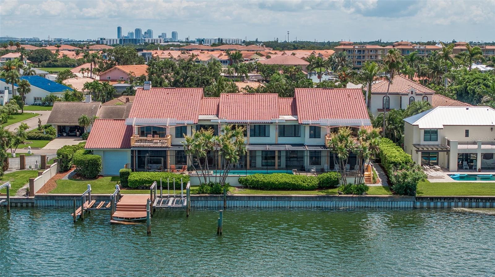 This 8677 sq ft home offers extensive living space with potential for personalization. The first floor features a family room with a fireplace, wet bar, and wine fridge, a kitchen with a walk-in pantry and breakfast nook, formal dining and living rooms, a laundry room, and a study/den. An in-law suite with a private entrance, kitchen, living room, half bath downstairs, and an upstairs bedroom, full bathroom, and walk-in closet on the second floor.
Upstairs, in addition to the in-law suite, there are four bedrooms, each with an ensuite bathroom and walk in closet. The primary bedroom suite is over 1000 sq ft, with two full bathrooms (one with a shower, one with a whirlpool garden tub), two walk-in closets, a private study, and a vanity. Both the primary and second bedrooms have water views and private balconies. The other two upstairs bedrooms have full bathrooms and walk-in closets.
The outdoor area includes a swimming pool and hot tub under a screen enclosure, a shaded dining area, and a patio bathroom with a shower. The property has two garages: a two-car garage and a larger one for a boat, RV, or 2-3 cars in tandem. A dock with a boat lift provides access to Tampa Bay and nearby boating destinations like Fort DeSoto Park, the Skyway Bridge, the Gulf of Mexico, and Anna Maria Island. The home is also close to some of the world's best beaches, downtown St. Pete, Sarasota, and multiple airports.