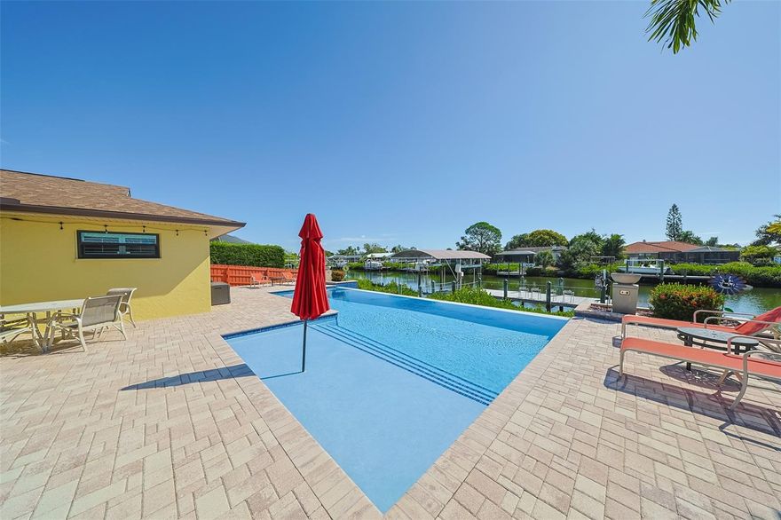 Welcome to the ultimate boater's and entertainer's dream home! This meticulously maintained 4-bedroom, 2-bathroom pool and waterfront retreat offers an unparalleled lifestyle, seamlessly blending luxury with functional living. Enjoy the peace of mind that comes with new roof and soffit, fresh paint and significant upgrades over the years, including Florida room with mini split AC, a tankless water heater for endless hot water, impact-resistant windows, 500 gallon propane tank for a generator, and a striking circular paver driveway that provides ample parking and excellent curb appeal. The true highlight awaits outdoors. The expansive paver deck surrounds a stunning infinity pool, creating the perfect setting for relaxation or grand gatherings. Beyond the pool lies a large dock leading to your private 14,000 lbs covered boat lift, offering direct access to the bay