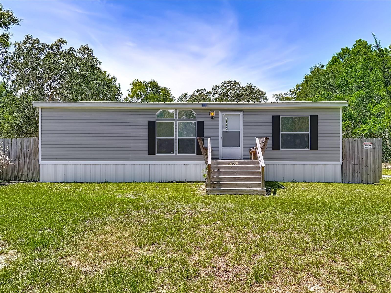 Welcome to your perfect blend of comfort, function, and country serenity. Nestled on a quiet, beautifully landscaped 1.10-acre lot on high-ground, this well-maintained 2002 built 2-bedroom, 2- full bathroom manufactured home with metal roofing offers a unique lifestyle with space to breathe and a host of very desirable amenities. The inviting living room flows seamlessly into the eat-in kitchen, fostering a sense of openness throughout the main living areas, whether hosting a gathering or enjoying a quiet evening. The eat-in kitchen provides ample space for all your cooking needs, complete with the necessary appliances. The spacious master suite features a large walk-in closet which includes a floor mounted safe for your valuables. The private ensuite includes a spacious walk-in shower. The 2nd bedroom is also generous in size, with direct access to the second full bath. The inside laundry room is conveniently located just inside the back door and has a full-size washer, dryer and added storage cabinets. Step onto either of the inviting front or back porches with built-in bench seating, ideal for enjoying your morning coffee or relaxing in the evening as you take in sweeping views of your serene acreage. Raised flower/vegetable beds, thoughtfully equipped with a water catchment system (including extra rain barrels for water storage) provide the perfect canvas for gardening enthusiasts to create their own floral retreat or edible bounty. For those who love to create or tinker, the property boasts a huge separate workshop complete with an accessible ramp, electricity, and air conditioning, along with two outdoor covered parking areas, making it the ultimate spot for hobbies, storage, or projects year-round. Also, a sturdy additional covered area with ample RV/boat parking, ensures your vehicles and recreational equipment stay protected from the elements. Safety and peace of mind are paramount here. The home is equipped with both an internal alarm system as well as an external Ring camera system. There is a separate Safety Shed (hurricane/tornado shelter) on a poured concrete foundation, rated for winds up to 250 mph. This structure has electricity, air conditioning, cabinetry, a safe as well as a futon for lounging or sleeping. This secure retreat ensures you and your loved ones are prepared for any storm, while still enjoying comfort and convenience. Additional features include a small storage unit for yard tools, a designated burn pit for cozy gatherings under the stars, and sturdy burn barrels to handle outdoor clean-up with ease and a sprinkler system. This property offers all the comforts of home, enhanced by practical outdoor features and a tranquil rural setting. Whether you’re seeking a peaceful primary residence, a weekend getaway, or a versatile retreat with room for all your interests, this unique listing is ready to welcome you. Lots of shopping and popular local dining options nearby. This home is minutes from the famous Weeki Wachee live mermaids, Pine Island Park and Roger’s Park for fun on the water. Close to the Suncoast parkway for quick access to the airport, Tampa, Clearwater and St. Pete Beaches (Ranked in the top 5 Beaches in the US), also close to the famous Tarpon Springs Sponge Docks. Enjoy everything Tampa Bay has to offer. Go just to the north and you’ll find Chassahowitzka National Wildlife refuge, Homosassa Springs, Crystal River & Cedar Key on the Suwannee Sound. Beautiful gulf and river boating & fishing