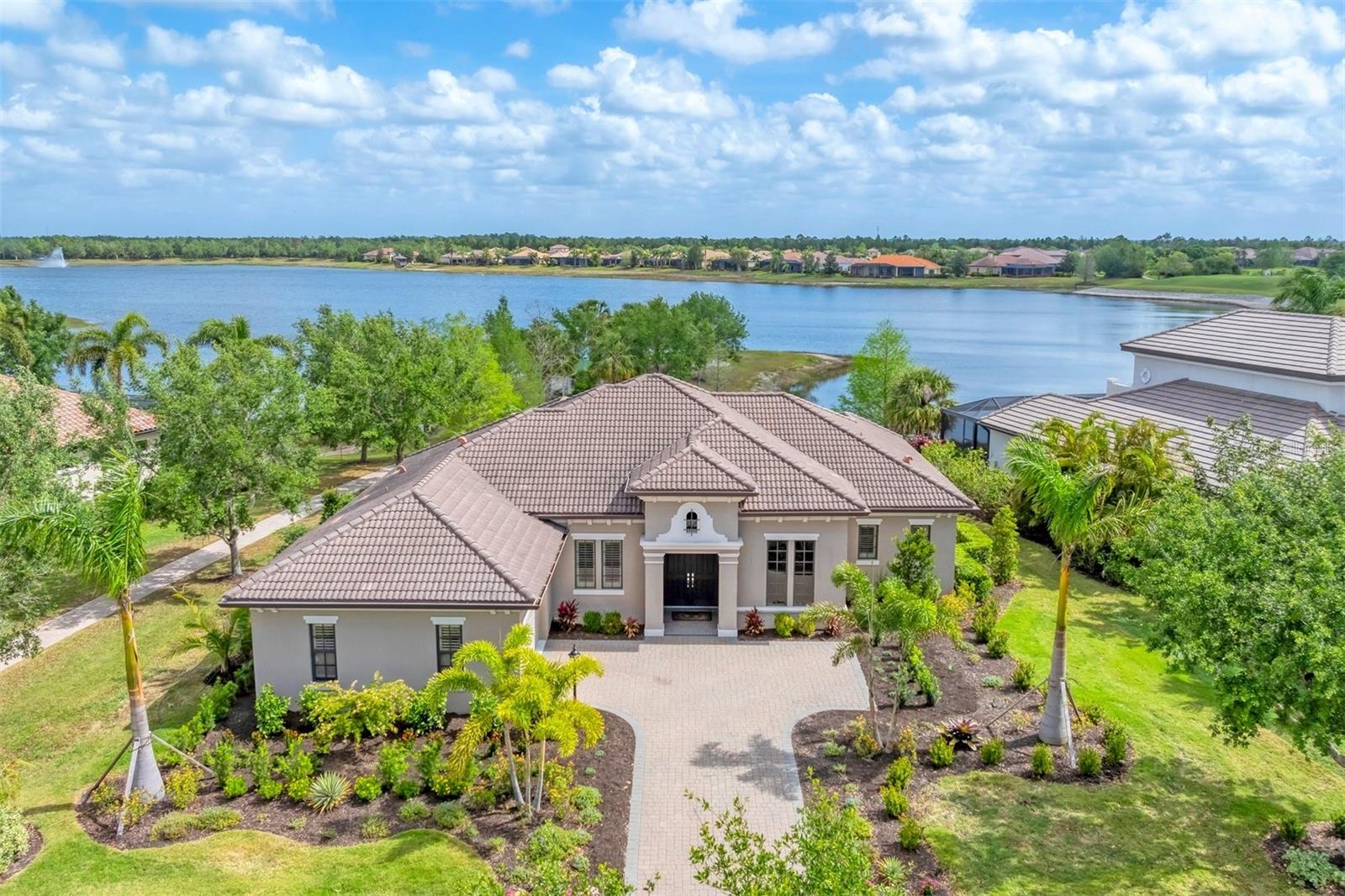 Welcome to this exquisite three-bedroom, three-bath John Cannon custom-built home, in the sought-after Country Club East neighborhood. Offering a blend of luxury, comfort and modern design, this home is a masterpiece, featuring a spacious layout and breathtaking lake and golf course views. From the moment you step through the double doors into the grand entryway, you'll be captivated by the expansive great room with tray ceiling, abundant natural light and pocketing hurricane-impact sliders leading to the lanai. This seamless transition between indoor and outdoor living creates the ideal space for entertaining, with panoramic views of the pool, lake and the lush Royal Lakes Golf Course. The gourmet kitchen is a chef’s dream, complete with two-tone cabinetry, granite countertops, stainless steel appliances, a walk-in pantry, under-cabinet lighting and a reverse osmosis water filtration system. The large island, with a breakfast bar and extra storage, makes cooking and entertaining a breeze. Elegant finishes throughout the home include tray ceilings, crown moldings, large-format tile, wood flooring and custom window treatments. The den off the great room, with French doors and wood floors, offers a quiet and sophisticated retreat. The primary suite provides an oasis of tranquility with expansive lake views. It features a tray ceiling, crown molding, a spacious walk-in closet and an ensuite bath with double sinks, makeup vanity, soaking tub and walk-in shower. Two additional generously sized bedrooms and baths provide privacy and comfort for guests. The large lanai is your outdoor sanctuary, offering panoramic views with unobstructed lake vistas and Royal Lakes Golf Course in the distance. Relax by the saltwater heated pool with sun shelf or entertain guests in the outdoor kitchen, complete with a grill, vent hood and a new Zephyr beverage cooler. Additional amenities include a whole-home water softener, updated landscaping with extra irrigation, a large paver driveway, a side-turned garage, and hurricane-impact windows and doors throughout for added peace of mind. Whether you're lounging by the pool, entertaining friends and family, or enjoying tranquil surroundings, this home promises to be the backdrop for your life’s cherished moments. Country Club East residents enjoy exclusive access to The Retreat, a neighborhood amenity center boasting a resort-style pool, fitness center and billiards room. Additionally, The Residents Club offers another pool, spa and a volleyball court for residents to indulge in leisure and recreation. For those seeking more recreational options, just a few streets away lies the Lakewood Ranch Golf & Country Club, featuring 72 holes of golf, 20 Har-Tru tennis courts, 20 pickleball courts, multiple pools, grand clubhouse, and The Lodge bar/restaurant. Residents have the option to avail themselves of these facilities through various membership packages. Discover this gem in Lakewood Ranch, America’s top best-selling, planned multigenerational community!
