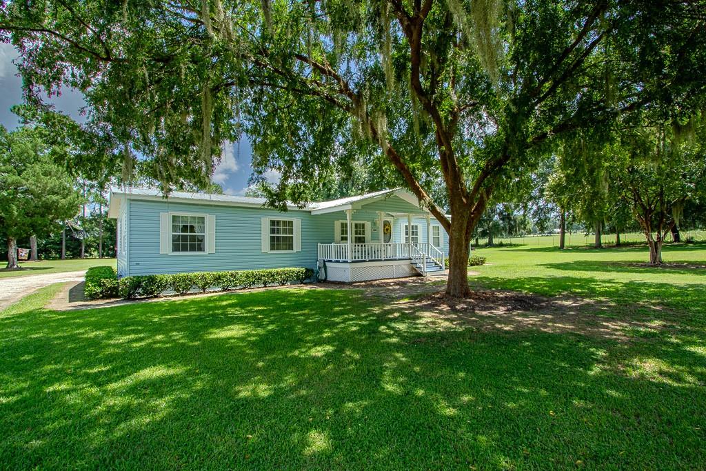 Immaculate 3BR/2BA + Office Manufactured Home with Workshop on Fenced Lot! This beautifully upgraded home sits at the end of a quiet subdivision, offering privacy, stunning views, and convenience—just minutes from Gainesville, Alachua, schools, and shopping. Inside, enjoy crown molding, bead board walls, luxury vinyl plank flooring, and a cozy electric fireplace insert (original chimney closed off at roof). The spacious kitchen features rebuilt oak cabinetry, a pantry, and broom closet. The owners’ suite boasts two large closets, dual sink vanity and walk in shower. Guest bath includes a tub/shower combo and freestanding vanity. Additional flex room perfect for an office or playroom with built in shelving. HVAC (2019), water heater (approx. 2020), and metal roof (2016). Exterior highlights include full fencing, lush landscaping, towering oaks, added gutters (2025), and an expanded septic drain field. Bonus 20x40 workshop with roll-up door, power, and lighting—plus a side lawn tool shop and rear utility shop. Move-in ready and meticulously maintained!