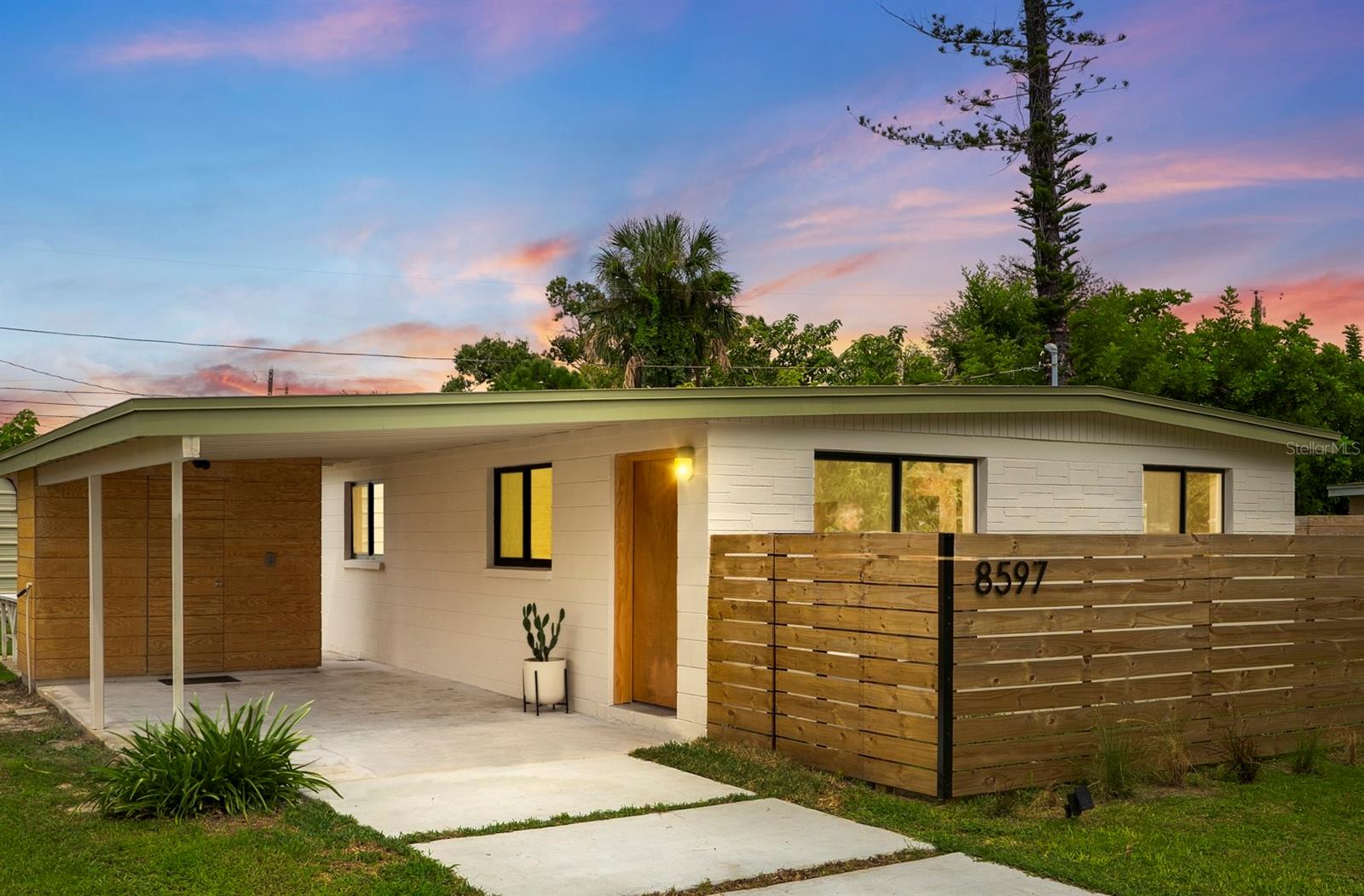 A mid-century ranch, reborn. This is The Turnaround House. For the admirer of minimalist, modernist design, this home has been thoughtfully renovated with inspiration from the greatest architects of our time. Clean lines, natural light and meticulous design defines each space. With the charm of an MCM home, it been masterfully renovated with new hurricane impact windows, new roof, new appliances, new HVAC with exposed industrial ductwork, new electrical, new plumbing, new indoor laundry and new fencing. Inside, discover custom built-ins, newly installed wood paneling with grain that flows seamlessly from ceiling to wall, immaculate trim work and polished terrazzo floors with the soft sheen of modern concrete. Set on an oversized lot along a quiet street, the property offers a carport, abundant attached storage, and an additional large shed ideal for a workshop. Outdoor spaces invite gatherings, with room in the backyard for a boat or RV. The front yard is graced with a mature mango tree and new concrete pavers, providing generous on-site parking. All of this, on a high-and-dry lot where flood insurance is not currently required. A rare find for this level of craftsmanship!