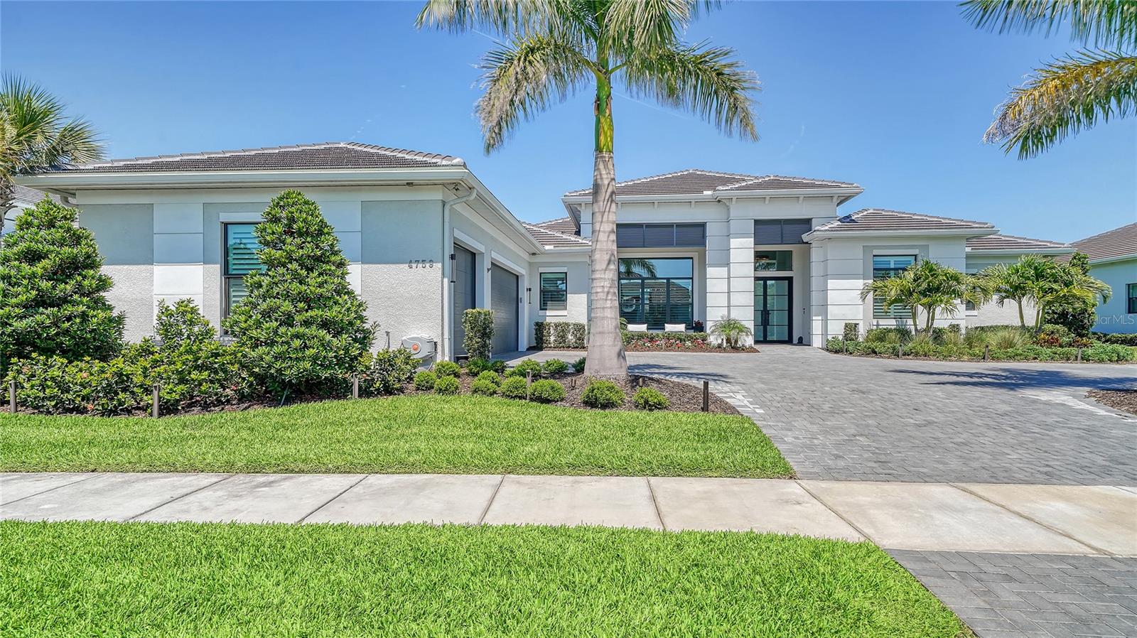 Stunning, better than new 4 bedroom + Bonus Room 4-1/2 bath home. One of Artistry's most desirable floorplans, built in 2021 on one of the best homesites in the neighborhood with lovely water & sunset views. The current owners spared no expense with substantial upgrades and a custom saltwater pool & spa with panoramic screening and a huge outdoor entertaining area. Done in a Coastal contemporary architectural style with double glass door entry, step inside to a sun-washed interior with 12’ ceilings, tall sliding glass doors, and plenty of windows providing great outdoor views. All windows and doors are upgraded Hurricane impact. French Oak flooring is throughout the entire home with the exception of the bathrooms. The layout emphasizes views, provides seamless indoor/outdoor living, and offers the privacy of a split floorplan with 4 en-suite bedrooms plus a study. A spacious bonus room offers space for a game room, home theater, or second living area. Other upgrades include plantation shutters & custom window treatments, modern lighting, foam insulation, barn doors, epoxy coating on 3 car garage flooring and expanded pavered driveway. The showcase kitchen is classic with white shaker cabinets, a 6 burner GE Monogram natural gas stove and high end appliances plus a luxurious island with Cambria quartz countertop, perfect for kitchen prep or casually hosting family and friends. The dining room is ideal for entertaining or elegant dinners and the kitchen area has plenty of room for a breakfast table. Outside, travertine decking surrounds the pool and expansive covered lanai, which provides shaded space perfect for enjoying refreshments as you gaze across the water. Artistry is a gated enclave lined with palm trees, tropical landscaping, and coastal architecture - a private neighborhood with the opportunity to make new friends. Luxury amenities include a community clubhouse, resort-style pool, and pickleball sport courts. Artistry provides easy access to Sarasota's world-class beaches, arts & culture, medical facilities, and dining options, while offering the serenity of an exclusive residential area.