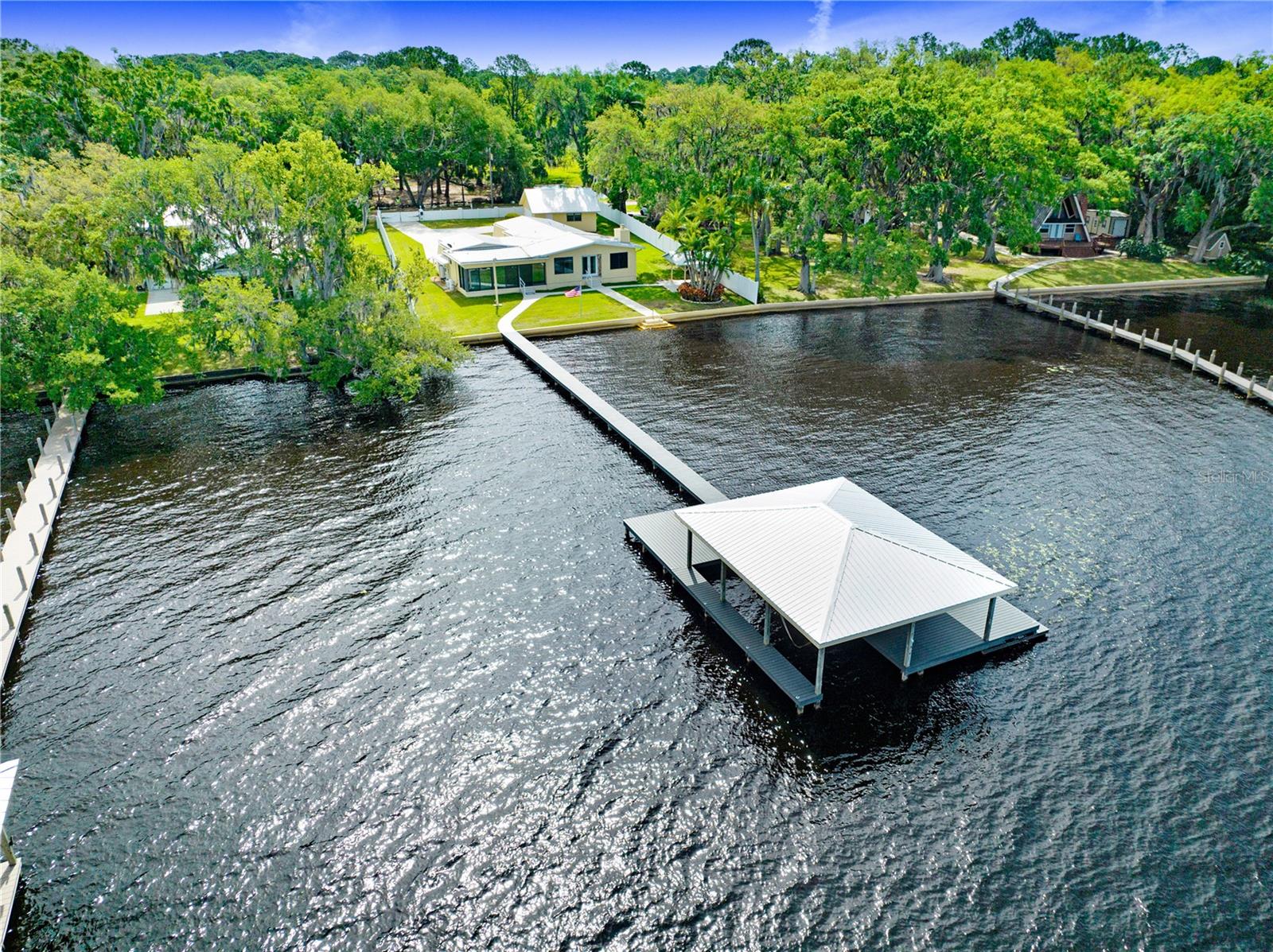 PRIME LOCATION/ALLIGATOR CHAIN OF LAKES in the Heart of St Cloud, this Lakefront home is truly a hidden gem, offering breathtaking water views and sunsets. Situated on the largest lake of the Chain, Alligator Lake, this property boasts an impressive 100 feet of lake frontage, setting the stage for an unparalleled outdoor haven. The composite decking dock, meticulously crafted with every detail in mind, alongside a boat lift and a covered boat house equipped with both water and electric, serves as your gateway to countless adventures on the water. The presence of a concrete sea wall ensures an added layer of privacy, making this haven a serene escape. The home itself offers luxury and versatility, featuring two owner's suites with one designed for utmost privacy. Its open floor plan is accentuated by windows and sliders that offer panoramic views of the shimmering water, immersing residents in the beauty of their surroundings.