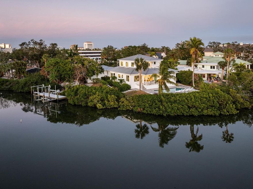 Welcome to an exceptional waterfront sanctuary on Hudson Bayou, this home is situated securely above the base flood elevation and experienced no flooding from the storms. With easy boating access to Sarasota Bay and breathtaking sunsets, you are also just a short stroll from downtown Sarasota’s vibrant cultural, culinary, and artistic scene. Situated on an oversized lot with lush, mature landscaping, this home is a serene, private retreat surrounded by nature’s beauty also safe and secure above the current flood zone. Upon entering through grand double doors, you are greeted by an open floor plan that exudes grace and style. Soaring ceilings, crown molding, and exquisite French oak plank floors create an ambiance of understated luxury, while serene water views provide a picturesque backdrop. The spacious great room features a gas fireplace and impact sliders that open onto an expansive deck with travertine marble flooring. Designed for alfresco living, this outdoor haven offers elegant dining and lounging areas framed by tranquil bayou vistas. The gourmet kitchen is a chef’s dream, complete with a Viking stainless steel appliance package, gas cooktop, quartz countertops, and an island breakfast bar that seats four. A large picture window above the sink brings the outdoors in, while the adjacent dining area, surrounded by glass windows, offers direct access to the deck and uninterrupted water views. Retreat to the tranquil primary suite on the second floor, where oversized windows and sliders open onto a private balcony, perfect for savoring quiet moments and taking in serene bayou views. This suite also includes a dedicated office with custom built-ins and a spa-inspired bath featuring an oval soaking tub, glass-enclosed shower, and porcelain tile. Three en-suite guest bedrooms on the main level provide comfortable accommodations, while an additional en-suite bedroom at the rear of the home ensures privacy for visitors. A versatile office/media room, complete with dual pocket doors and a bay window seating area, offers endless possibilities. Outside, a large pool surrounded by travertine decking and framed by lush greenery creates an oasis of relaxation. A private boat dock with Trex decking and two boat lifts invites you to embark on water adventures. Additional highlights of the home include a temperature-controlled wine room, PGT impact-resistant windows and doors, metal roof, whole-house vacuum system, gated entrance and a three-car garage. This exceptional property also boasts a charming treehouse with water views, adding a touch of whimsy to the grounds. Located steps away from Marie Selby Gardens, the bay front marina, and downtown Sarasota, and a short drive to area beaches, this home offers the perfect blend of tranquility and comfort. This property is currently in an Opportunity Zone through 2025. "Opportunity Zone" qualifications to be verified by buyers and buyer’s representatives. Substantial renovation completed in 2023, every aspect of the home has been upgraded, the effective year built is 2017.