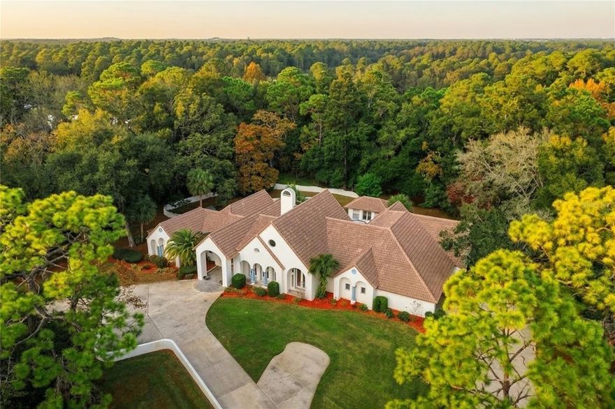 One or more photo(s) has been virtually staged. In the heart of the coveted, gated Sweetwater Club an executive enclave long associated with legacy ownership and understated wealth rests this architecturally distinguished estate on a quiet, tree-lined street. Set on an extraordinary 1.45-acre homesite, the property unfolds like a private park, with mature canopy trees and a natural setting that feels both secluded and timeless.

This custom-built residence offers a generous split-bedroom floor plan with 4 bedrooms and 5.1 baths, thoughtfully designed for both grand entertaining and everyday living encompassing over 6,200 sq. ft.  Lovingly maintained by its owners, the home presents a rare opportunity for the discerning buyer who values space, architectural character, and the freedom to curate interiors to suit a modern lifestyle.

A dramatic arrival begins through Old-World mahogany entry doors, opening to stately columns and a floating ceiling that sets an immediate tone of elegance. The formal living room is anchored by a wood-burning fireplace, a beverage bar, and four graceful arched doors that flood the space with natural light.  Adjacent, the formal dining room is framed by marble flooring, wood-trimmed doorways and columns and a soft, neutral palette, offering a refined setting for memorable gatherings.

The kitchen is richly appointed with natural wood-toned cabinetry, expansive preparation space, a center island, and stone countertops providing both functionality and a strong foundation for future enhancement. Overlooking the kitchen, the family room makes a striking impression with soaring ceilings, paneled walls, and an intimate stone-etched wood-burning fireplace that serves as a focal point of warmth and character.

The primary suite is a true retreat, featuring vaulted ceilings, decorative stained-glass accent windows above the bed, laminate flooring, an oversized custom-fitted closet, a sunken soaking tub, and even a dedicated fitness area—an indulgent sanctuary within the home. Each of the four additional bedrooms is generously sized and privately appointed, offering en-suite baths and walk-in closets, ideal for family or guests.

Outdoors, the property transforms into a private Florida oasis. The pool and lanai are surrounded by lush greenery, offering serene views beneath a canopy of mature trees and exceptional privacy. Adjacent to the pool is a secondary dwelling, 200 Sq Ft, complete with a living area, kitchenette, and bath perfect for guests, multigenerational living, or a private retreat.

Recent improvements provide peace of mind while preserving the home’s character, including a new tile roof 2025, newer plumbing fixtures, tamper-proof outlets, updated switches, new bedroom flooring, and a refreshed interior palette. Completing the outdoor experience is a private pickleball court, an unexpected and coveted amenity rarely found in estates of this caliber.

Residents of Sweetwater Club enjoy exclusive access to 285-acre, spring-fed Lake Brantley, nestled within the Wekiva watershed, along with an impressive array of amenities: 10 tennis courts, basketball courts, playgrounds, a fishing dock, boat ramp, and a sandy beach overlooking unspoiled waters and endless skies.

This is not simply a home it is a canvas of enduring architecture, land, and location, awaiting thoughtful personalization.