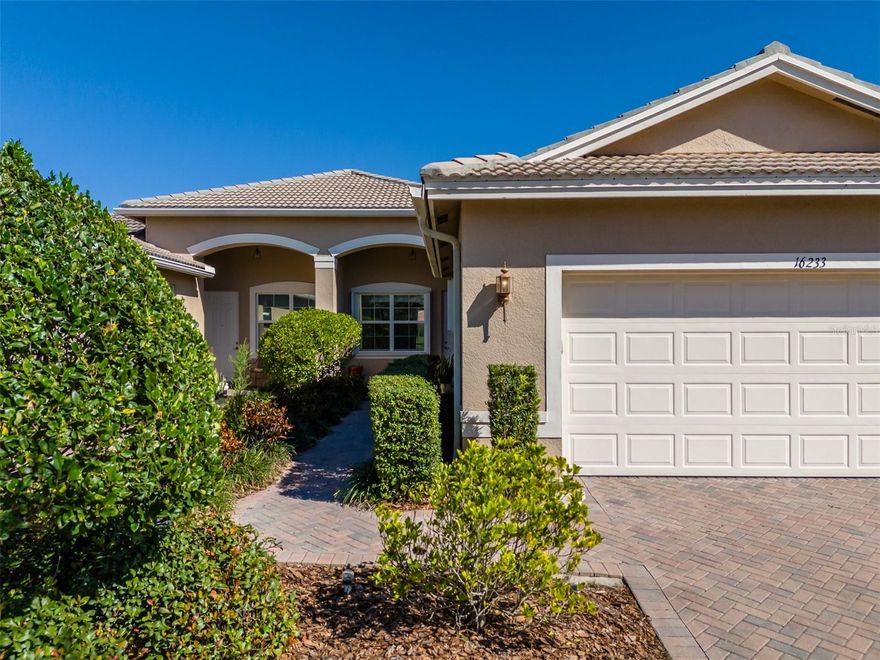 Discrete, quality comfort aptly depicts this CRISTINA villa. Built by GL Homes and located in Valencia Lakes, Tampa Bay's premier 55+ Active Adult community, this CRISTINA’s 1,317SF provides ample space to live your idyllic life. The pristine brick pavered driveway leads to a long walkway along manicured gardens leading to the front portico. Relax and enjoy Tampa’s amazing sunsets from the front porch. Upon entering the villa, you will be immediately drawn to the amazing water view at the rear of the villa but first take a few moments to explore the simple beauty within. The open floorplan boasts a quaint dining room, a well-sized great room and a wonderful kitchen with a dinette. 17”x17” ceramic tile on the diagonal graces these floors. The dinette will comfortably host eight persons, and it has a wonderful view of the front gardens. The spacious great room features a lighted ceiling fan and a 12’ slider leading to the lanai that provides am amazing view of the lake out back. The kitchen features white cabinetry, CORIAN counters with a double sink and a reverse-osmosis water faucet, and a bar-height counter, a closet pantry, and white appliances to include a GE dishwasher, GE range, Whirlpool fridge, and a dinette which is perfect for daily or intimate meals. The custom sculpted valence on the dinette window is particularly impressive. The primary bedroom is at the rear of the villa and features a ceiling fan, a 6’ window overlooking the lake which provides glorious sunrise views, and a comfortable ensuite bathroom. The ensuite features a single vanity with two sinks, a walk-in framed glass shower, a water closet for the commode and a large walk-in closet. Bedroom 2 is at the front of the villa, and it affords generous space, excellent privacy and comfort. The 4-piece guest bathroom and the ensuite bathroom are equipped with sturdy safety bars. The laundry room is adorned with a Whirlpool top-load washer and dryer and a built-in closet. Environmental comforts are assured by a front & rear of house gutters, a DAIKIN 4-ton 15 SEER variable speed HVAC with an Airflow UV-C light system coupled to a ComfortNet SMART wi-fi enabled thermostat, a 50-gallon Rheem water heater with recirculating pump (2020), a Culligan Iron Soft Plus water softener system, a 200 AMP Square D main electrical panel, and all windows are protected by hurricane rated accordion shutters. This CRISTINA is spacious and compact at once and it is built with exemplary quality, and it can be yours if you seize the day.