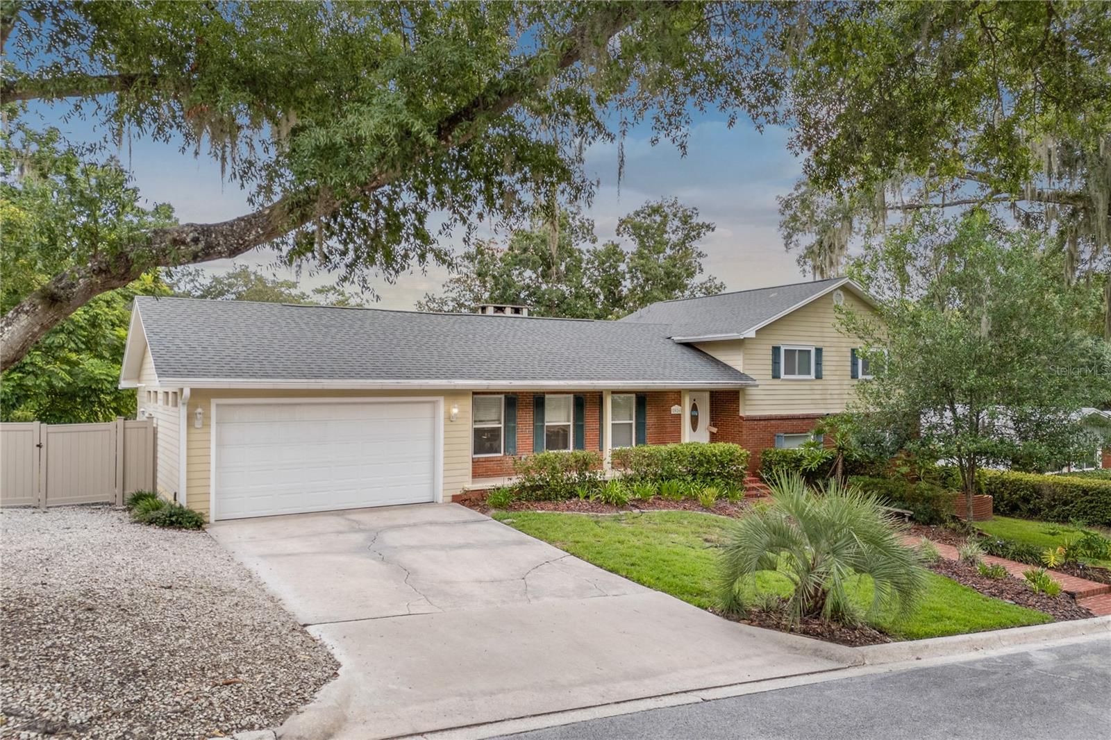 Located in one of Northwest Gainesville’s most beloved and enduring neighborhoods, this beautifully renovated 5-bedroom, 3-bathroom home in Forest Ridge offers nearly 2,500 square feet of living space on over a third of an acre, just minutes from the University of Florida. With no HOA and a neighborhood known for its pride of ownership, this property delivers both flexibility and charm in a setting that feels established, quiet, and connected. The interior has been thoughtfully updated throughout, beginning with brand-new luxury vinyl plank flooring that spans the main living areas and an inviting brick fireplace that anchors the spacious family room. Enhancing the space is a professionally installed 7-speaker in-ceiling surround sound system featuring high-end GoldenEar speakers—ideal for immersive movie nights or entertaining. The kitchen is a standout, featuring granite countertops, custom cabinetry, a large center island, stainless steel appliances, a subway-style tile backsplash, pendant lighting, and a walk-in pantry with its own exterior access—perfect for unloading groceries or serving a future outdoor kitchen. The layout offers excellent privacy and function, with a split bedroom plan ideal for guests or multigenerational living. The oversized primary suite features a private exterior entrance and a stunning en-suite bath with dual vanities, granite counters, a spa-worthy walk-in shower with frameless glass, and a vintage-style clawfoot soaking tub. A second bedroom also includes its own private bath, offering guests or family members an added layer of comfort and autonomy. The remaining bedrooms are generously sized with easy access to the home’s third fully updated bathroom. Additional highlights include a dedicated walk-in laundry room, a two-car garage, and an elevated covered front porch that offers a peaceful view of the tree-lined street. Out back, a covered and screened lanai flows seamlessly to a spacious open deck, all overlooking a fully fenced and beautifully landscaped backyard with ample room for play, entertaining, or future additions like a pool. From its classic curb appeal and smart updates to its rare combination of size, location, and functionality, this Forest Ridge home is a truly exceptional opportunity in Gainesville’s residential core.