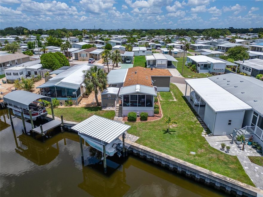 Were you searching for a WATERFRONT HOME with an 8,000 lb BOAT LIFT in an active 55+ GATED Community? Welcome to this well-maintained 3 bedroom, 1.5 bath, FURNISHED home with 1,060 square feet of living space, located in the desirable Caribbean Isles Residential Cooperative. Built just 10 years ago, this home features sturdy 2x6 sidewall construction.The spacious, open, SPLIT-BEDROOM floor plan is designed for both comfort and functionality. You will enjoy the Florida lifestyle from your 12x15 waterfront lanai, featuring low-maintenance Trex decking. The like-new boat lift at your PRIVATE DOCK is perfect for accessing the canal that leads directly to Tampa Bay. And in addition, there are three off-street parking spaces. Caribbean Isles is a resident-owned, active 55+ gated community offering a wide range of resort-style amenities: clubhouse, heated pool, indoor and outdoor shuffleboard, bocce, horseshoes, game room, craft room, library, and more. Regular activities include bingo, water aerobics, coffee socials, exercise and craft classes, live music dances and parties, and group excursions. For boaters and outdoor enthusiasts, the community includes a boat ramp and kayak launch with access to beautiful mangroves, wildlife, and spectacular sunsets. Manatee and dolphin are often seen swimming in the canals. RV and utility trailer storage is available to residents for just $120 to $250 annually. The community is pet-friendly, and golf cart-friendly with approximately four miles of paved roads. Adding to the value of the home is the reasonable monthly maintenance fee of just $242 and NO CDD or LOT RENT.