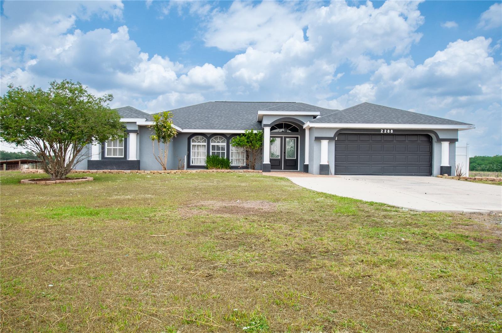 The impressive, gated entryway is a fitting welcome to this delightful 4-bedroom, 2-bathroom, 5.1 acre agricultural property. The interior designer of the household will appreciate the creative possibilities presented by the stylishly and naturally illuminated open floor plan, with its neutral color palette. Vaulted ceilings add comfortable airflow and a sense of spaciousness across 2,898 sq ft of AC living space that features all newer wood plank tile throughout. The expansive chef-inspired kitchen is newly updated in the popular peninsula layout, which creates ample space for food prep and bar height seating. Your cutting board will look great on the beautiful granite countertops, while premium Samsung smart appliances keep the place running. In light that is both stylish and natural, this headquarters of culinary endeavor makes even just staring into the open fridge seem like the start of a great meal. The recently updated ensuite primary bedroom, conveniently located, is roomy and tranquil. In addition to the convenience of the private bathroom (walk-in shower, statement piece copper tub), you will find ample closet space to let your wardrobe breathe. The other bedrooms, quiet, and with plenty of closet space, also offer’s the convenience of privacy with the split floor plan and pocket door division. The large yard is attractively landscaped. A driveway with ample accommodation for visiting vehicles leads to an attached two-car garage that is available for its original purpose or for use as additional flex space. As an open-air extension of the home adding an additional 2,000+ sq foot of paver patio and lanai is an ideal platform for outdoor furniture sets and the gatherings that naturally follow. Make (or dodge!) a splash in the swimming pool, the social and sapphire centerpiece of the rear of the home that has also received updates. The home is found on a pleasant street located in the county. You'll enjoy relaxing views of the greenbelt and the swimming pool. Move out to the back of the property where you’ll be delighted to have access to a 40x40 livestock/horse barn, an additional 30x48 workshop and a new oversized chicken coop. This delightful dwelling is a special DeSoto County find located in flood zone X.