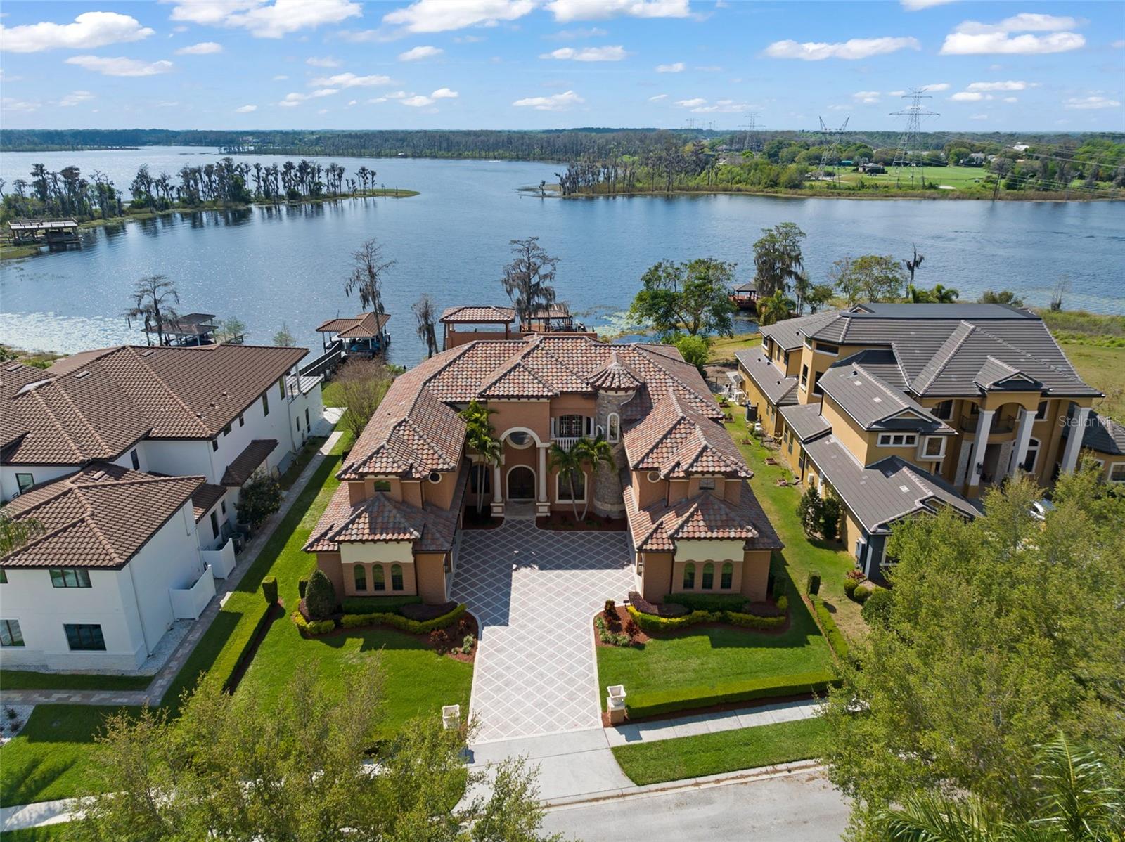 Welcome to a residence where the essence of lakeside opulence meets the prestige of Bay Hill's championship golf course, creating a haven of unparalleled sophistication and relaxation. Lying within the guard-gated community of Emerson Pointe, this is more than just a home—it's an exquisite retreat where luxury meets lifestyle in perfect harmony. The epitome of charm and elegance embodies this custom lakefront home, nestled along Lake Chase, one of the famed Windermere Chain of Lakes. With close to 100 feet of lake frontage, this exquisite property offers a lifestyle of unparalleled luxury. Here's your exclusive chance to immerse yourself in the coveted Florida Chain of Lakes lifestyle where boat life becomes an integral part of daily living. Picture yourself spending leisurely days cruising along the tranquil waters fishing or simply soaking in the breathtaking scenery. Elevated on a little over 1-acre lot, the estate cascades down to the scenic waterfront, complete with a dock, covered/tiled boat lift, and double jet ski lift, inviting you to indulge in the ultimate lakeside living experience. Every corner of this home is meticulously designed for both comfort and sophistication. Enjoy 7 bedrooms, 7 full and 1 half baths, a home theater, a wine cellar, and an office. Step into the lavish embrace of a recreation sanctuary, a haven crafted for indulgence and leisure. The gourmet kitchen is a chef's dream featuring stainless steel appliances, a 48-inch refrigerator, 6-burner gas stove, pasta spigot, custom-made cabinetry, and beautifully crafted Giallo granite countertops all accentuated by wood beams overlooking picturesque views of the tranquil waters. The primary suite, complete with a gas fireplace, is a sanctuary of luxury and tranquility offering unparalleled vistas of the tranquil waters below. Overlook the Butler Chain from the second and third-story balconies which capture panoramic vistas of the nightly Disney fireworks that captivate the senses and soothe the soul. Recent upgrades include a $315,000 new roof and renovated balconies, ensuring both timeless elegance and structural integrity. Other amenities include: 24-Hour Guard, 6 garage stalls, onyx master bathroom countertops, central vac system, Tesla charging station, elevator, exterior travertine pavers, summer kitchen, and so much more. Whether unwinding with a cinematic masterpiece in the plush confines of the media room or engaging in lively gatherings with loved ones, every moment will be cherished. Additionally, indulge in the vibrant culinary scene just moments away at Restaurant Row, where a multitude of dining experiences await. Golf enthusiasts will appreciate the proximity to Bay Hill's Country Club, offering unparalleled opportunities to perfect their swing on pristine fairways. Here, luxury living seamlessly blends with the convenience of nearby amenities, ensuring a lifestyle of sophistication and leisure. Bedroom Closet Type: Walk-in Closet (Primary Bedroom).