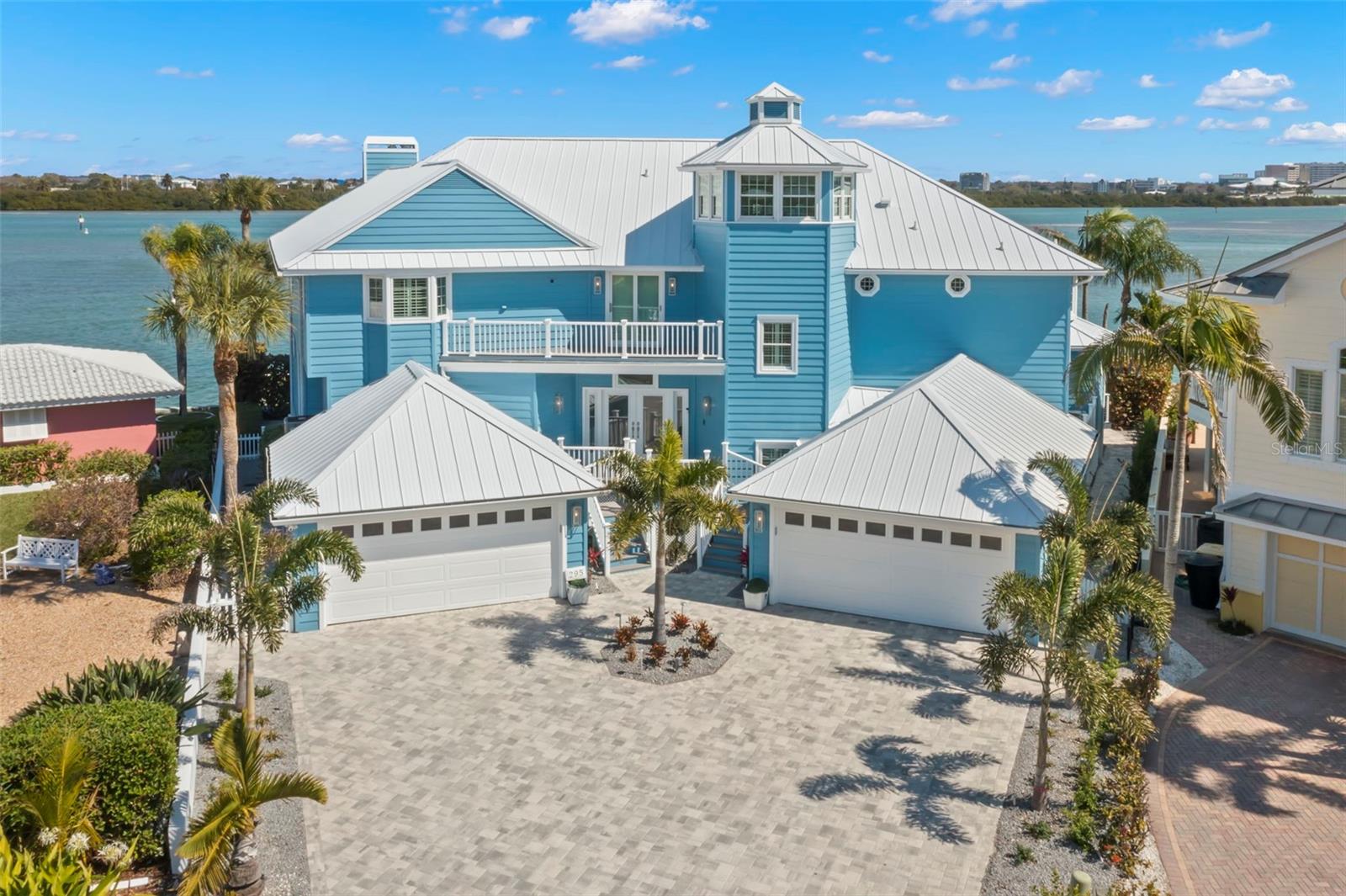 HIGH AND DRY and exactly what you want in a luxurious waterfront property. Welcome to 295 Bayside Dr in Clearwater Beach & is located on one of the best lots with WIDE OPEN WATER VIEWS! This home is a testament to coastal elegance & modern luxury, seamlessly blended in this waterfront masterpiece. This beautiful 5 bedroom, 4.5 bath home with just over 5,000 SF of heated living space being sold TOTALLY FURNISHED & is MOVE IN READY! Short walk or Golf cart ride to the beach. This home not only offers mesmerizing sunrises from your back area & unparalleled dolphin sightings but also endless sunsets from your front balcony & crows nest that is currently being used as a home office. You will be captivated by the 180-degree views of the Intracoastal Waterway, downtown clearwater & Clearwater Bay/Harbor. The home has been recently updated & transformed to blend the charm of a beach house with contemporary sophistication, showcasing meticulous attention to detail with state-of-the-art updates. The kitchen is a chef's dream, custom cabinets, elegant countertops, & new high-end appliances, breakfast bar & center island. The master bathroom's remodel introduces sleek cabinetry & modern mirrors, enhancing both ambiance & functionality. Significant upgrades have been made to the entertainment spaces, including a chic wet bar with extra storage ensuring seamless hosting and daily living. Exterior enhancements include a new white metal roof and maintenance-free decking providing endless outdoor enjoyment. New metal cable & vinyl railings, alongside refreshed exterior paint, enhance safety & aesthetics. The interior has been updated with new flooring in guest rooms, plumbing, and electrical have been updated, Savant audio, visual, and lighting system installed throughout the home, coupled with Lutron light switches, offers unparalleled control & ambiance. Landscaping and strategic outdoor lighting accentuate the property's architectural beauty, with the swimming pool area boasting a new salt generator, LED lighting, and remote capabilities. The driveways and garages have been updated for added durability and style, including new garage door components & an epoxy-coated finish plus a new mini split AC unit was installed for extra comfort while working in the garage. The home's layout promotes luxury and comfort, with warm tones & shiplap walls highlighting water views. The main level includes a family room with fireplace & a wall of windows to enjoy the water views, dining room, bedroom with ensuite, formal dining room, living room & kitchen. Make your way up the beautiful staircase to the upper level that houses the primary retreat that is 26 x 23 with a wall of windows for water views, a fireplace, vaulted ceiling with tongue and groove finishing. Ensuite with dual sinks, large vanities for lots of storage, garden tub plus a large walk in shower with multiple shower heads, & large walk in closet. All of the upstairs rooms have access to the wrap-around balcony to enjoy the water views! The outdoor space features a resort-style swimming pool, fire pits, & a party dock, complemented by a covered boat dock with lift, electricity & water plus Jet Ski lifts. This recent renovation focused on modern luxuries but has also preserved the property's coastal charm. Prime waterfront location, comprehensive updates, & intrinsic beauty, this residence offers a unique blend of luxury, comfort, & sophistication, making it a truly exceptional home in Clearwater Beach.