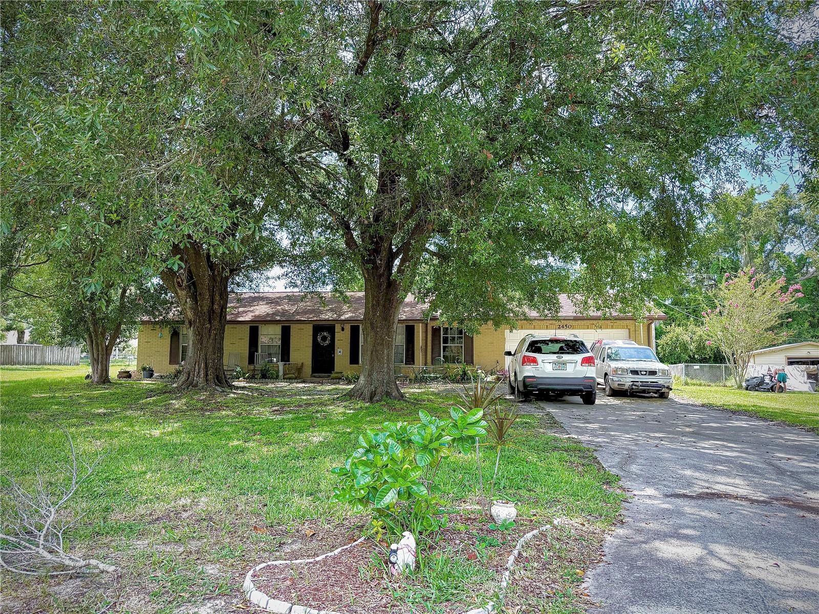 Sitting on one of the largest lots in the neighborhood, this North Lakeland home is a rare opportunity to own nearly half an acre (.44 acres) with NO HOA or CDD! Tucked at the end of a cul-de-sac in a quiet, well-established neighborhood, this home is full of character and potential — the perfect canvas to make your own. The massive backyard is truly the star — wide open, shaded in the front by mature trees, and private in the back with plenty of room to garden, build, host, or relax and watch the sunset. Whether you dream of a fire pit, pool, swing set, or all of the above, this yard gives you the space and freedom to do it. Inside, the home features a classic split-bedroom layout with real hardwood flooring throughout the main areas and tile in the wet zones. The spacious living room flows into a separate dining room and leads to the retro-style family room featuring a real brick, wood-burning fireplace, and wood paneling. There's even an extra storage closet in the family room, just before you step out through sliding glass doors into that incredible yard. Down the hallway, you’ll find all three bedrooms: two guest rooms on the left, an updated full bath and linen closet on the right, and the oversized primary suite at the end of the hall. The primary offers two closets, a large vanity space, and a private toilet/shower area. The two-car garage is another standout — perfect for storing toys, tools, or turning into your dream workshop, gym, or hobby space. Plus, there's a dedicated laundry area for added convenience. This isn't your average cookie-cutter home. It's got space, charm, and freedom — ready for you to bring your vision to life.