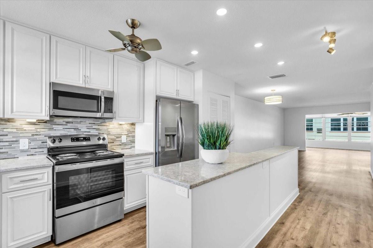 Be the first to live in and experience the beauty of the many updates in this condo! Enter the unit through the storm door with a retractable screen. You’ll immediately notice the fresh interior paint, recessed lighting, and gleaming luxury vinyl plank flooring in all the main living areas--which makes your feet happy!  The open kitchen features quartz countertops, tile backsplash, a large island with storage galore, stainless steel sink with nickel fixtures, stainless steel appliances.  Enjoy the marina view while working in this gorgeously renovated kitchen. The wide baseboard gives the floors that extra touch of beauty.  A complete bathroom renovation awaits you with a large vanity with quartz top and sleek modern fixtures, double medicine cabinets with mirrors (providing lots of storage), lighting, glass shower doors, and tile walls and flooring. The bedroom has a large walk-in closet and new carpeting, ceiling fan, plus a cool soothing wall color.  The Florida room makes a great office nook or spot to enjoy a glass of wine. You will agree the unit has been thoughtfully and beautifully updated with designer touches throughout.  Town Shores is a sought-after 55+ community with tons of amenities and Fun!  Measurements are approximate and not deemed reliable.