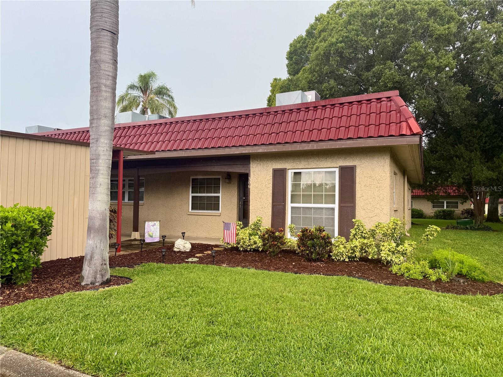 Welcome to Pinewood Village, a beautifully maintained 55+ community nestled among mature oak and palm trees. This end-unit villa offers easy single-story living with a newer roof, an open floor plan, and a thoughtful split-bedroom layout for added privacy. Enjoy your morning coffee or afternoon reading in the bright sunroom overlooking the open yard space behind the home. Interior features include an in-unit laundry closet with washer and dryer, blinds throughout, and optional furnishings for a simple move-in. The assigned covered carport and nearby centralized mailbox add to the everyday convenience. Pinewood Village offers a warm and welcoming atmosphere with a community recreation center, exercise room, pool, ping pong and billiards tables, and a full calendar of activities throughout the year. Internet and cable are included in the HOA. No pets allowed - community rules. Ideally located close to shopping, dining, medical services, and entertainment.