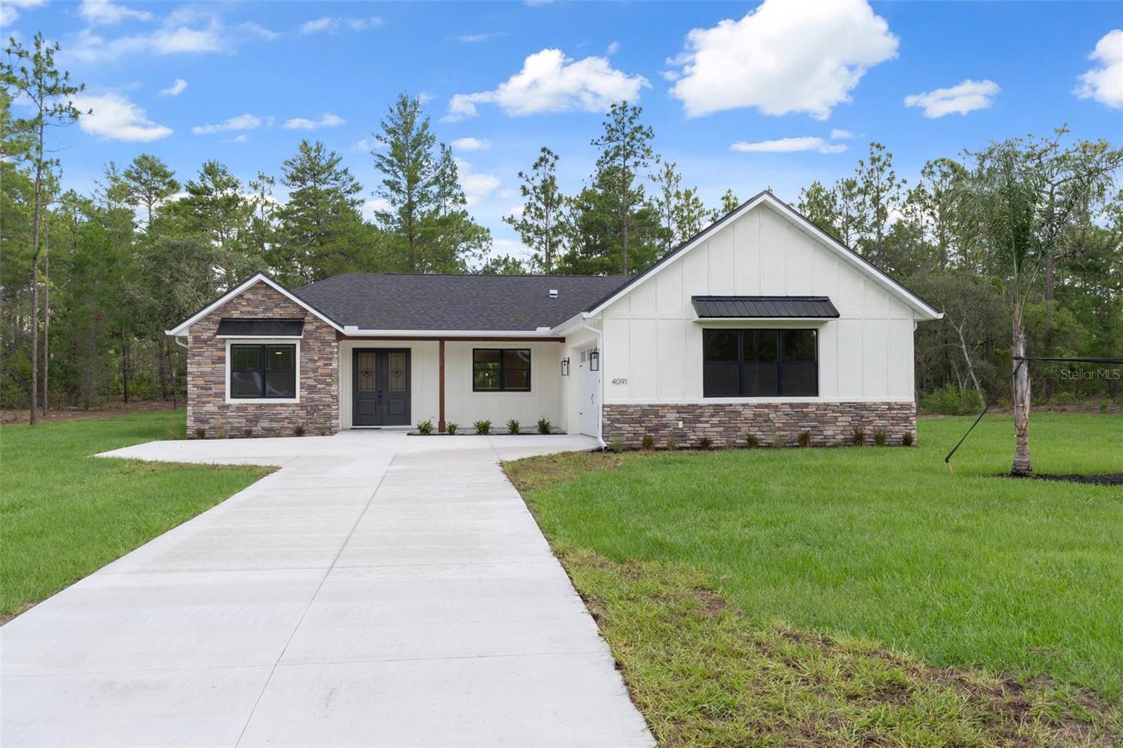 One or more photo(s) has been virtually staged. Welcome to this beautifully crafted new construction home in Pine Ridge Estates, where European-inspired charm meets modern Florida living. From the moment you arrive, the warmth of stone & wood accents, an inviting front porch, and a courtyard-entry two-plus car garage create a striking first impression. Inside, 9'4" ceilings, 8' doors, luxury vinyl plank flooring, and recessed LED lighting throughout create a light, bright, and welcoming atmosphere! The expansive great room serves as the heart of the home, thoughtfully designed for both living and dining, with a recessed tray ceiling and 12' pocketing sliders that seamlessly blend indoor & outdoor living. The kitchen is as functional as it is stylish, with a central island offering breakfast bar seating and a full suite of stainless steel Whirlpool appliances, including a French door refrigerator and convection oven w/air fry mode. A supersized butler’s pantry expands prep & storage space while maintaining design continuity, with ample outlets for small appliances. The spacious laundry room continues the streamlined aesthetic and features a Samsung Super Speed Steam SmartThings washer & dryer. The primary suite is a serene retreat with a tray ceiling, generous bedroom space, and double French doors opening to a paver patio, plus a luxurious en-suite bath with walk-in shower, water closet, and a custom walk-in closet complete with center island and transom window that invites natural light while preserving privacy. A secondary suite offers ideal accommodations for guests or multi-generational living with a walk-in closet, full bath with walk-in shower, and private lanai access, while a third generously sized bedroom also includes a walk-in closet. The guest bath is beautifully finished with a deep soaking tub, extended vanity, and linen closet. Set on a tranquil home-site surrounded by nature, this thoughtfully designed residence offers timeless finishes, cohesive design, and peaceful living in the heart of Pine Ridge Estates. INQUIRE about the Distinctive Features & Comforts...