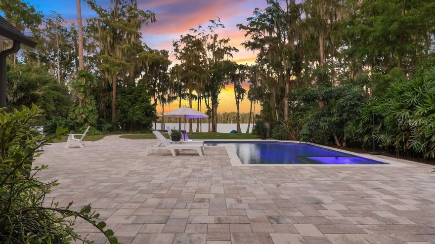 One or more photo(s) has been virtually staged. The largest combined parcel along this stretch of spring-fed Lake Pickett, offering unmatched flexibility for homesteading, multi-structure living, or long-term generational use. Gated and private, the property supports trailers, RVs, boats, equipment, and expansion, featuring a stand-alone garage, water-toy shed, greenhouse pergola, fruit trees, custom fencing, and a lakeside gazebo. Whether kept as one private compound or divided, this estate delivers space, functionality, and value rarely found near Orlando.
The 4,094 sqft renovated home includes 4 bedrooms and 4 baths, a 3-way split layout to include a private upstairs retreat and separate guest wing. A 2023 central kitchen anchors the open living and dining spaces all with lake views. White-oak wood-look tile runs throughout the main floor, while the 2023 primary suite offers a calm, modern retreat.
Indoor-outdoor living shines with a gas and electric option heated pool (2022), pavered deck, retractable screened porch, and outdoor shower. Mature oaks, long water views, and cleared acreage combine beauty and functionality for a rare lakefront lifestyle — all just minutes from East Orlando, 408, and 417.