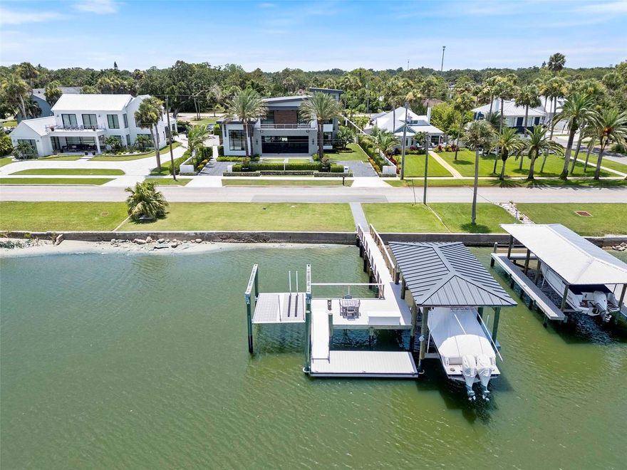Waterfront Modern Masterpiece! Walled estate home featuring five bedrooms, five full bathrooms, one half bath and multiple indoor and outdoor areas for entertaining or complete privacy. Created from multiple parcels and spanning from the Indian River across S. Riverside Drive to Magnolia Street, this .63 acre property features over 4,200 sq. ft. under A/C and over 6.700 sq. ft. in total living space. The private waterfront features a custom dock, a covered boat slip w/ 10,000 lb. lift, a separate floating dock and a jet ski/kayak platform lift. Inside this magnificent home you are welcomed into grand and inviting open floor plan living. Every space is filled with light and maximizes both water views and immediate access to adjacent outdoor living spaces. Gorgeous wide plank white oak floors run throughout the living spaces creating a natural flow and continuity. Custom wood ceiling panels (w/ cove lighting) naturally define the spaces and create a casual elegance to this magnificent custom home. The Kitchen features integrated Subzero refrigerator/freezer, Wolf natural gas cooktop with 6 burners plus griddle and pot filler, Wolf wall oven and Wolf wall microwave oven, Wolf warming drawer and a Bosch integrated dishwasher. Huge kitchen island for family and friends to keep you company in the kitchen and to share a casual meal. Steps away is the Miele coffee station and wet bar, with ice maker, for that jolt of java and happy hour. Behind the scenes you'll find a drop zone and large laundry area adjacent to the three car garage. The drop zone and laundry area include washer/dryer, cabinetry, stainless utility sink and a custom bench and rack for rain coats, gardening shoes and everything you want to leave out of sight. The Butler's Pantry features even more storage, deep stainless sink, a 2nd Bosch dishwasher and a 30" Subzero dual zone wine refrigerator. Also on the ground floor is the river view primary suite with a spa quality ensuite bathroom and enormous custom walk-in closet. The primary bathroom has separate vanities w/ backlit mirrors, garden air tub, huge walk-in shower and private water closet with bidet. A large, ensuite, Bedroom #2/Bathroom #2 is also located on the ground floor along with a separate half bath/power room for guests. Opening directly from the fabulous living areas you'll find a lanai with Summer Kitchen featuring DCS natural gas grill, sink and refrigerator. Beyond the lanai is a sparkling pool and spa, both heated with natural gas. As if that's not enough, beyond the pool you'll find a separate cabana with natural gas fireplace. Both the lanai and the cabana feature motorized retractable "noseeum" screens and mini-split A/C units. Upstairs you are welcomed by the stunning Eastern views to the Intracoastal from the spacious loft/billiard/media room. From the loft area you have immediate access to a full bathroom and the large riverfront balcony. Also upstairs are Bedroom #3 (riverfront and ensuite with walk-in shower), Bedroom #4 (ensuite with tub/shower) and Bedroom #5 (currently used as a home office). 1010 S. Riverside Dr. features smart home technology with smart hub, motorized window shades, lighting controls, audio controls and climate controls. Don't worry about the weather forecast, the natural gas powered whole house back-up generator will keep you cool. Walking distance to the Vibrant Canal Street Scene and the Yacht Club. Mere minutes to Flagler Ave. and Beach. Ideal Florida Luxury Living!