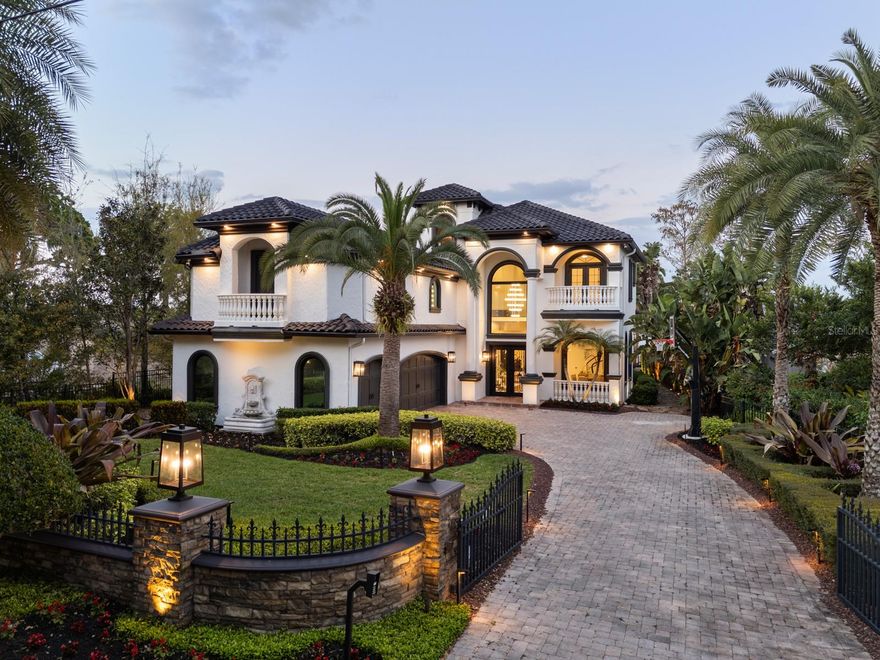 Experience the epitome of lakefront living on the Butler Chain of Lakes with this exceptional Windermere estate. On one of the area’s desirable streets, this home offers over $350,000 of recent luxurious upgrades, including a new kitchen and fireplace, new windows and doors, landscape lighting, new landscaping, a newly painted exterior and roof. The home also boasts a newly added $85,000 dock, designed by Docks of Orlando, providing direct access to the tranquil waters of Wauseon Bay. With 5,639 square feet of meticulously crafted living space, this estate offers an unparalleled living experience with stunning views of one of the most peaceful parts of the Butler Chain of Lakes. Upon entry, you are welcomed by a grand two-story foyer and formal living area, designed to invite relaxation and luxury. Expansive views of the resort-style pool and spa are framed by a breathtaking floating 650-gallon arched saltwater fish tank, providing a breathtaking view of the bay. The formal living room features a beautifully sculpted paneled wall, illuminated by soft ambient lighting, which enhances the room’s refined elegance. Continue your journey through the first floor to find your incredible gourmet kitchen, accompanied by a wet bar, wine refrigerator, oversized pantry with a custom swinging door, a Wolf and Sub-Zero appliance package, quartz countertops, custom cabinetry and new lighting illuminating the space. Gracefully sharing this remarkable space is your sophisticated living room, where a striking fireplace, enveloped in exotic stone and framed by bespoke cabinetry with refined wooden accents, serves as a breathtaking focal point. The newly renovated primary suite, on the first floor, offers a private sanctuary with more panoramic views of Wauseon Bay. The regal en-suite bath features Christopher Guy lighting, dual vanities, a standalone soaking tub and a Schonbek Da Vinci chandelier overhead. A temperature-controlled wine cellar is conveniently nearby, along with a well-appointed laundry room, an additional bedroom and a full bath on the main floor. A stunning staircase wrapped with curved glass railing leads to the second floor, where you’ll find a custom 195-square-foot wall clad in custom copper-patinated iron. This home also features a residential elevator finished with wood paneling interior and a stainless steel SICIS tile floor. The private cinema is one of a kind, with custom eucalyptus wood millwork, a glass bar top illuminated by LED lights, Busby cabinetry, ample storage, Sub-Zero appliances, two under-counter wine refrigerators and luxurious seating beneath a starry sky ceiling. Step outside to your expansive private balcony, offering scenic views of the lake and spectacular Florida sunrises, all framed by glass railings and AstroTurf flooring. The second floor also includes three additional bedrooms, three full baths and a second laundry room, ideal for guests or family. The outdoor living area features a summer kitchen and ample room for relaxation, embodying the best of Central Florida’s luxurious lakefront lifestyle. For car enthusiasts, the three-car air-conditioned garage, with RaceDeck tile flooring and a custom storage system, is the ultimate addition. An exclusive respite, this home represents a refined, opulent lifestyle inside and out.