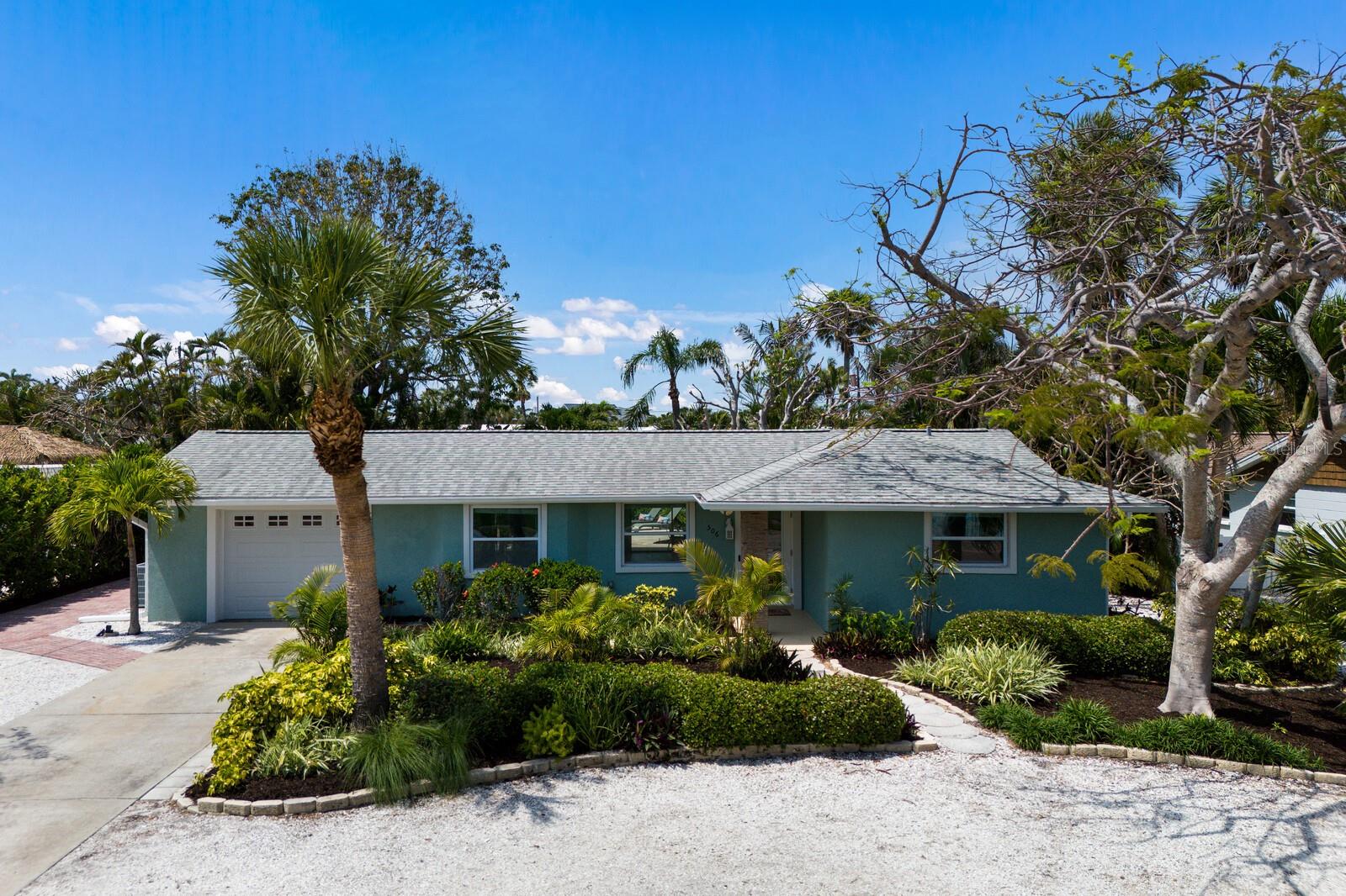 This easy living 3 bedroom, 2 bath home combines comfort and accessibility, offering a tranquil retreat in the heart of Holmes Beach with a beautifully updated interior and a lush, private backyard oasis. Wrapped in mature tropical landscaping, the outdoor space is ideal for unwinding, featuring a heated pool, an outdoor shower, a cozy firepit area, and plenty of shaded spots perfect for afternoon siestas. Inside, the open concept layout enhances the flow between living and dining areas, with pocket sliders that open fully to a spacious rear porch creating a seamless connection to the outdoors and making entertaining a breeze. The completely remodeled kitchen is a true highlight, showcasing crisp white cabinetry, sleek countertops, and stainless steel appliances, blending everyday functionality with modern flair. A generous island with seating and chic pendant lighting adds to the inviting atmosphere. Just off the kitchen, a flexible nook provides a perfect spot for casual meals or a tucked away workspace. The primary suite offers a peaceful escape, complete with a large ensuite bath featuring a walk-in shower, double vanity, and accessible design. Additional features include a one-car garage with a freshly coated floor. Located just a short golf cart ride from the beach, shopping, and dining, this move in ready home delivers easygoing island living with an elevated touch.