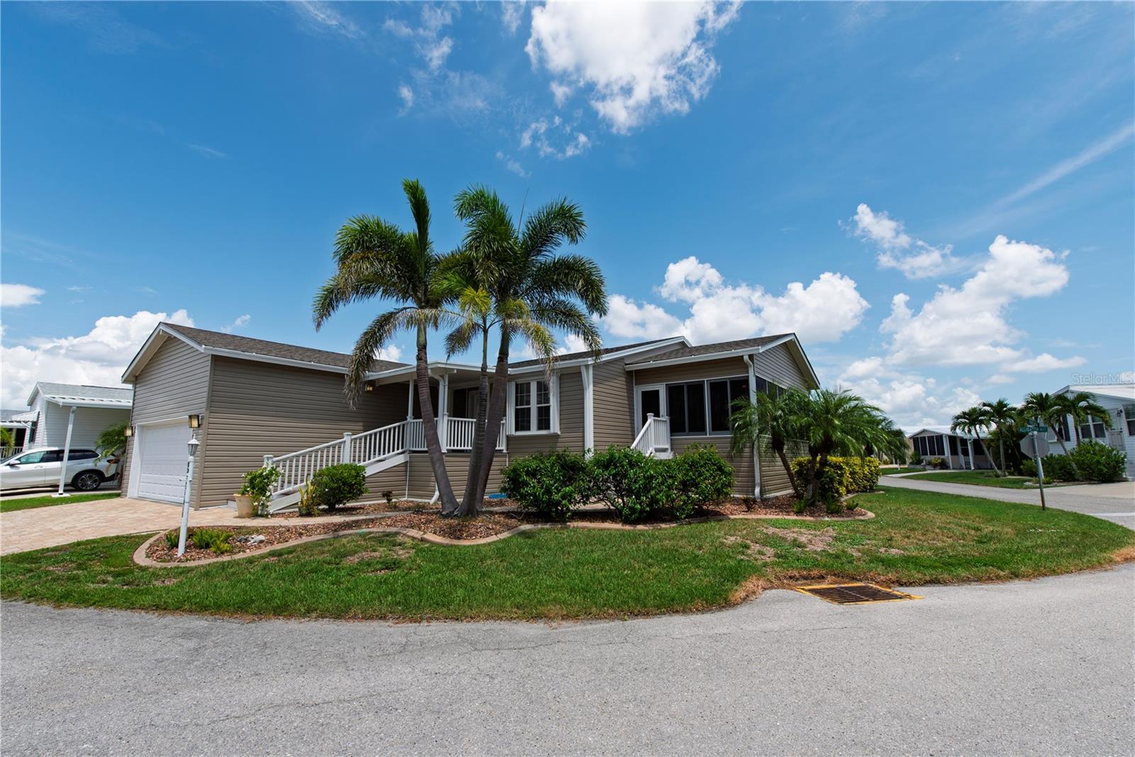 Nestled in the vibrant 55+ Windmill Village community, this stunning 2014 Palm Harbor home offers 2,030 square feet of spacious living. Featuring 3 bedrooms—or 2 bedrooms with a versatile office—and 2 bathrooms, this residence boasts high ceilings, elegant crown molding, and dry wall throughout. The main living areas showcase stylish tile flooring, while plush carpet adds warmth to the bedrooms. The expansive kitchen is a chef’s dream, equipped with solid wood cabinets, granite counters, breakfast bar and a large pantry, GE oven, microwave, cooktop, dishwasher, and an LG refrigerator, complemented by a new garbage disposal installed in 2025. The dining area impresses with a sophisticated coffered ceiling. Enjoy year-round comfort with a new AC installed in 2019 and a large enclosed lanai featuring Easy Breeze windows. The home is topped with a newer shingle roof, protected by accordion hurricane shutters, and includes transferable flood insurance. Additional highlights include a two-car garage with extra storage, an electric garage door opener, and an irrigation system, making this home a perfect blend of luxury and practicality. The $261.00 monthly HOA covers water, trash, sewer, lawn maintenance, and common building upkeep, making this home a perfect blend of comfort and convenience. This active lifestyle community features two private marinas, boat ramp, trailer storage yard, horseshoe pits, shuffleboard, bocce ball, billiards, indoor pickleball, a large community center and many clubs catering to your hobby interests. The Pavilion by the heated pool offers an area for holding gatherings. Punta Gorda was voted “#1 Best Small Place to Live” by Money Magazine and Forbes. Purchase price does not include $18,285.00 for Buy-In Share and Bond, which is refunded when you sell. Don't miss the opportunity to make this thoughtfully upgraded and beautifully maintained home in Windmill Village yours! Schedule your showing today-this is your paradise.