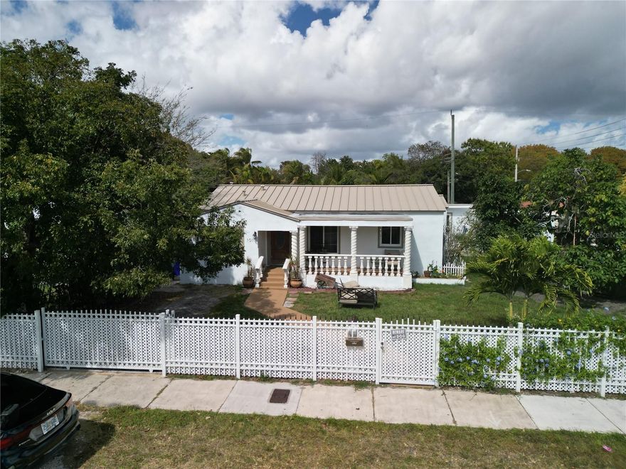 <LAST PRICE REDUCTION> This is a rare opportunity in the heart of Miami, set on an absolutely massive oversized double corner lot in one of the city’s most rapidly growing neighborhoods. With expansive land and significant development potential, this property offers flexibility for a discerning homeowner or a value-driven investor looking to capitalize on location, scale, and long-term upside.                                                                                               Positioned on a spacious corner lot, the home welcomes you with a charming front porch framed by decorative columns and a fully fenced yard that enhances both privacy and curb appeal. The extended driveway provides abundant parking, while the expansive green space offers endless possibilities- from outdoor entertaining and future additions to a resort-style backyard transformation. A private rear patio further elevates the outdoor living experience, creating multiple zones to enjoy the property’s impressive footprint. Inside, the home unfolds with bright, open living spaces finished with sleek tile flooring, recessed lighting, and a seamless flow ideal for both everyday comfort and elevated entertaining. The expansive living and dining areas are filled with natural light and anchored by a stylish feature wall that adds depth and character. The kitchen has been thoughtfully updated with granite countertops, custom cabinetry, stainless steel hood vent, subway tile backsplash, and a generous peninsula with bar seating- combining elegance with functionality. A fully permitted addition adds meaningful square footage and versatility, featuring a private office, adjoining bedroom, and a spa-inspired bath with glass-enclosed shower- perfect for guests or a sophisticated in-law suite. The primary suite offers a custom walk-in closet and an elegantly finished ensuite bath, while additional bedrooms and baths maintain a cohesive, modern aesthetic. At the rear of the home, a covered and screened patio creates a true indoor-outdoor living experience, complete with tiled flooring and ceiling fans overlooking the expansive yard — extending your usable space year-round. The grounds are beautifully complemented by mature greenery and lush trees, including cashew, soursop, avocado, and Dominican cherry, along with fragrant rosemary and oregano that enhance both the landscape and lifestyle appeal. The laundry room is thoughtfully positioned just off the one-car garage and offers ample storage and workspace, while the garage itself provides added flexibility for organization, hobbies, or additional utility space.                                                                                                                                Major improvements have already been completed, including a brand-new metal roof installed just two months ago, a newer AC system under two years old, and well-maintained electrical, plumbing, and water heater systems. With no HOA, the property allows for rare freedom and flexibility in today’s market.                                                                                                 Oversized land, permitted square footage, modern upgrades, and a premier central location just minutes from the airport, Downtown Miami, Wynwood, the Design District, and the beaches- this is a distinguished opportunity for a homeowner seeking space and sophistication or an investor recognizing the value of scale in a high-growth area.
