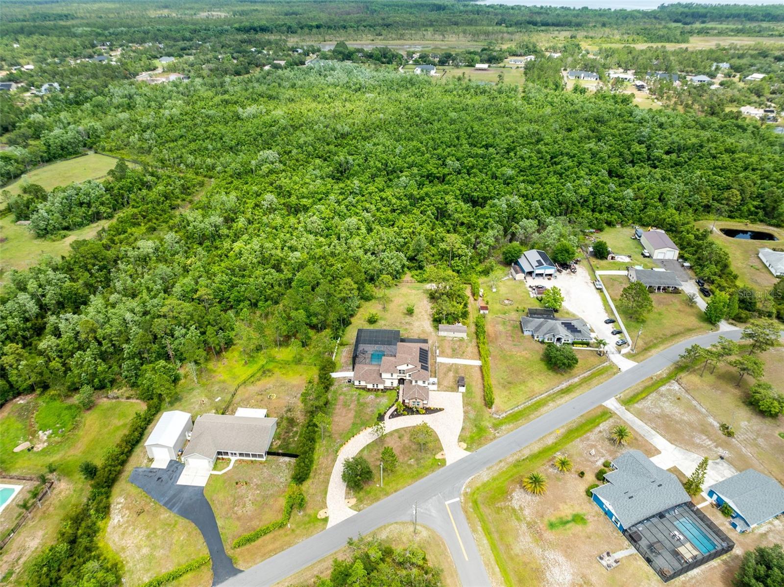 Relaxed Luxury in the Country… absolutely GORGEOUS custom home with separate In-Law Suite and OVER 3 Acres! Get ready to trade traffic for trees (3.15 acres of them, to be exact!!). If you've been looking for a property that offers room to roam with all the bells & whistles, then Look No Further >>>>> Welcome to a home that seamlessly blends indoor and outdoor living while offering quality, comfort, and just the right touch of casual elegance. Located in one of St. Cloud's most popular & desirable neighborhoods, this property is actually TWO HOMES; offering a beautiful and separate In-law suite that is affectionately described as a 'Casita' and includes 2 spacious bedrooms, 2 full baths, a fully-equipped second kitchen, and a cozy living space - making it ideal for multi-generational living, extended stays, or even as a private home office or creative studio. Providing so much versatility... this property is zoned for horses, situated on over 3 usable acres (over 1 acre currently cleared and fenced) **and** no flood zone or HOA restrictions! A truly unique property that offers more than a pretty house, it's a lifestyle! The main residence offers 3 large bedrooms and 3 1/2 bathrooms (**5 bedrooms / 5.5 baths in total**) and features an open-concept layout that showcases soaring 25-foot ceilings, floor-to-ceiling windows, 18-ft retractable sliding glass doors that connects the outdoor space expertly, and is anchored by a chef-inspired kitchen boasting double islands, solid wood cabinetry, granite countertops, stainless steel appliances, and dual sinks. But that's not all, a spacious loft and two balconies on the second floor offer additional living and relaxation space with views of the stunning pool area and surrounding landscape.
The outdoor living space features a spectacular retreat with an oversized saltwater pool and spa (solar heated) under a 25-foot screen enclosure, surrounded by stone pavers and mature landscaping. In addition, you'll find a dedicated RV parking complete with utility hookups, plus an oversized septic system to accommodate future additions. Over 2 of the remaining acres maintains its natural character with cleared trails suitable for exploring, birdwatching, or recreational use - and with No HOA restrictions, you can make this anything you heart desires!
The construction of this home is top-notch with energy-saving features like foam insulation in the walls and ceilings, high-foil radiant barrier on the first floor, a whole-house water filtration and softener system, irrigation well, and an oversized anti-gravity septic system. The attached 2-car garage is slightly oversized, and includes a storage bump-out, while the detached garage can accommodate additional vehicles and has electricity connected so it's the perfect space to be used as a workshop.
Bay Lake Ranch is a golf cart–friendly community known for seasonal neighborhood events and offers convenient access to area lakes, parks, conservation trails, and downtown St. Cloud. A short drive to Lake Nona Medical City, Orlando International Airport, and even the beautiful Brevard County beaches!