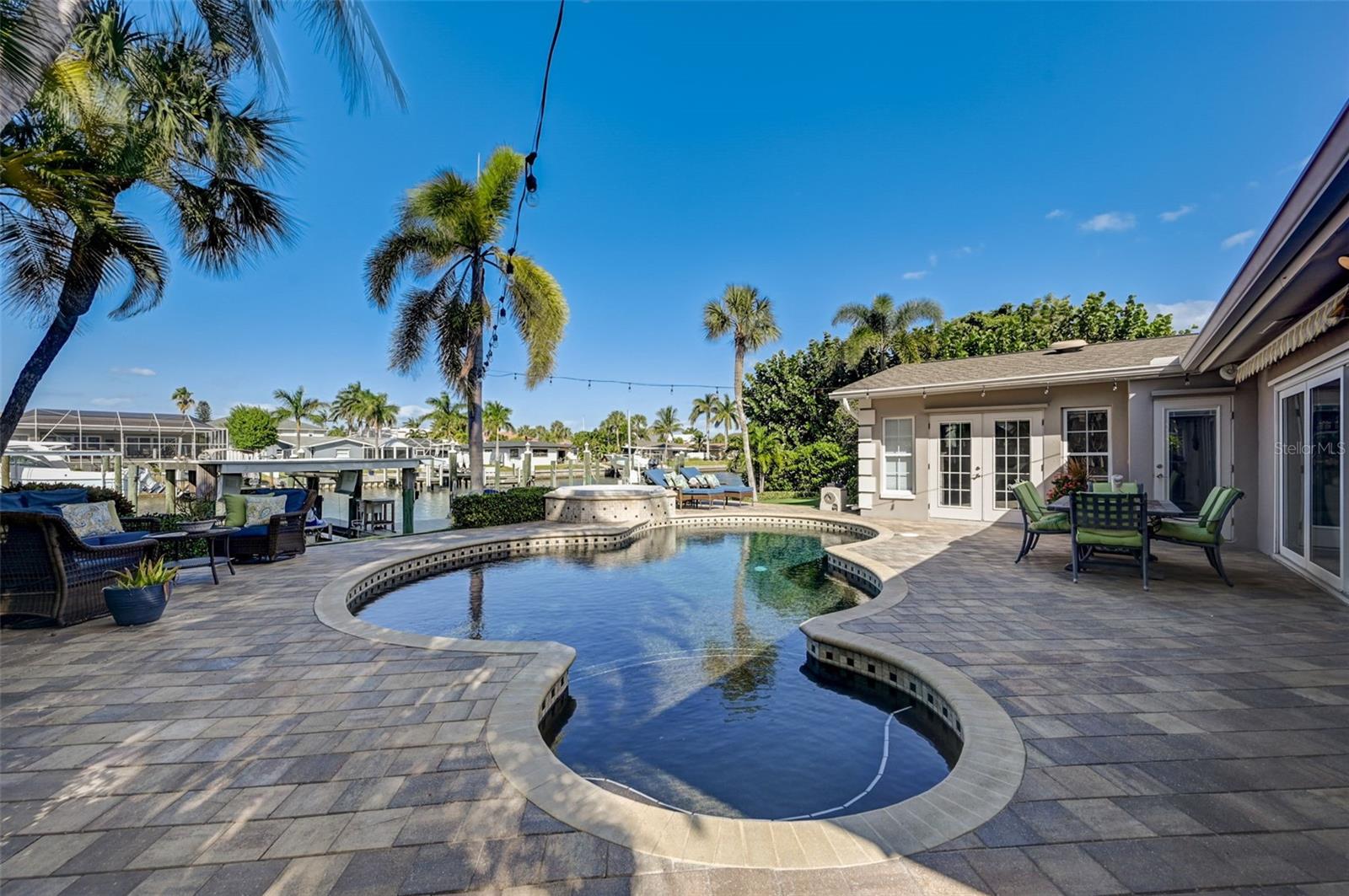 Impeccable Waterfront Home with immediate boat access to Tampa Bay - With 85' waterfrontage, 12-15' Deep Water and a new seawall, this home can accommodate 3 watercrafts including 1 boat (covered w/ 12K lbs lift), jet ski (on lift) and a Sailboat (pilings in place). Entire property has been fully updated with taste and style. Magnificently large kitchen is an organizer's dream. Luxurious primary suite is full of light and offers 2 walk-in closets and a 5-piece bathroom. Both guest bedrooms are generously sized as well. The back yard is perfectly designed for entertainment and gatherings featuring a gorgeous saltwater pool & spa (both heated), retractable awnings on remote that automatically close when winds are over 15 knots, surround sound in living room as well as the back yard. 2017 Roof, 2023 HVAC, 2021 Hot water heater, 2021 Composite dock and much more.