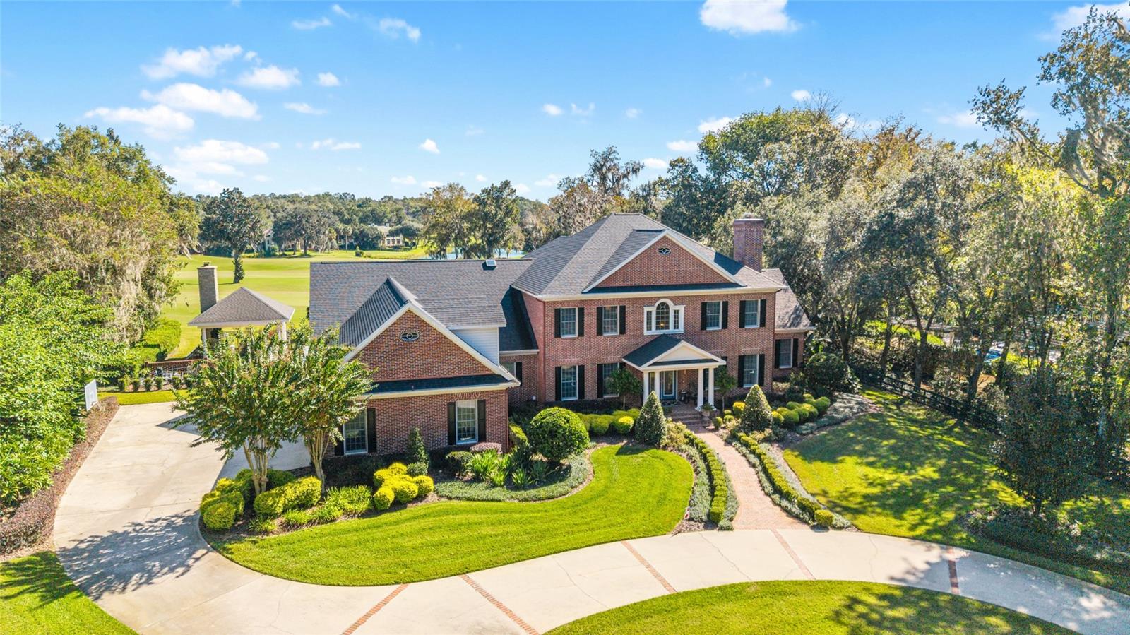 This stunning two-story red brick estate offers timeless charm, modern updates and breathtaking golf course views overlooking the 15th hole and beyond. Featuring 4 bedrooms, 3 full baths and 2 half baths, every space has been thoughtfully designed for everyday living. Step through the foyer and you’re greeted by a custom staircase leading to the second floor of the home. The main floor features a formal living room with a fireplace and mantle that have been beautifully updated, a spacious formal dining room and a family room that extends 2 stories, where walls of windows fill the space with natural light. A second wood-burning fireplace framed by custom built-ins anchors this inviting gathering space. The gourmet kitchen, fully remodeled in 2018, truly is the heart of the home with white wood cabinetry, gorgeous granite countertops, double ovens and a thoughtful layout that opens to a breakfast area and cozy sitting room, complete with a built in cabinet and beverage bar. The refinished hardwood floors flow beautifully throughout this space, extending to the staircase that leads to a large bonus/media room. The primary suite, completely redesigned in 2023, has exquisite finishes and a spa-inspired bath. Up the main staircase, you’ll find a loft area with a built-in desk and three additional bedrooms, with two sharing a Jack-and-Jill bath and one with a private ensuite, both featuring updated showers and modern touches. Outdoors, enjoy your own private oasis. The saltwater pool, fully redone in 2024 with new marcite, stone and updated pool equipment is surrounded by beautiful bluestone pavers and is fully fenced with a gate for privacy. Entertain year-round under the 25' x 25' pavilion, complete with a wood-burning fireplace and TV hookup, making it the ultimate space for weekend gatherings or quiet evenings by the fire. In addition, the grounds are beautifully landscaped and enhanced by extensive landscape lighting. Additional highlights include an air-conditioned and tiled 3-car garage, perfect for a workshop or home gym. The laundry room update (scheduled for completion December 2025) will feature custom cabinetry matching the kitchen for a cohesive, elevated look throughout the home. This home also has a tankless hot water heater, whole house generator, brand new sub zero refrigerator and all electric drapes. Don't miss this one in the beautiful Country Club of Ocala.