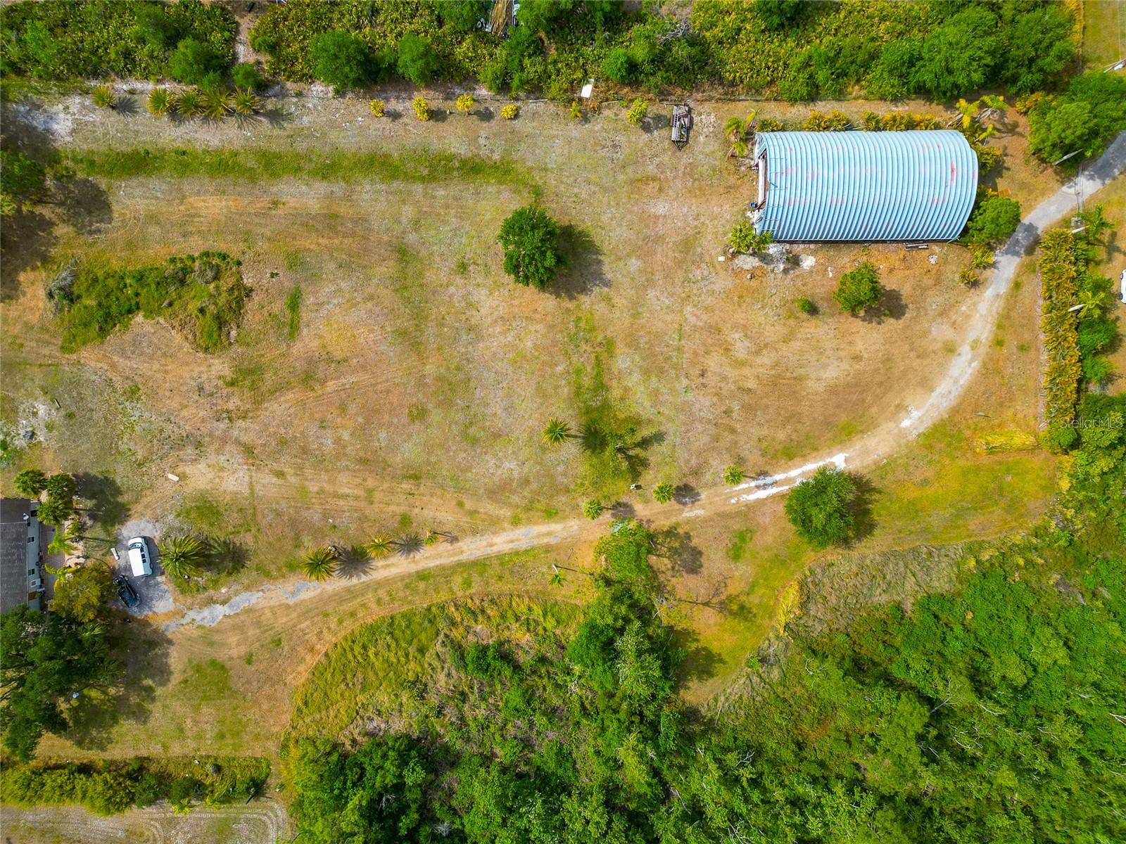 4.81 beautiful acres near the end of a private dirt road, extremely quiet area. This land is mostly cleared and fenced with some trees and a large pond that was previously stocked with fish. There is a 5000 square foot "hangar" outbuilding/ metal barn with an office inside that has electricity available to the building. The home on the property is 960 square feet with 1 bedroom 1 bath with an open kitchen and dining/living room combination. There is also a large bathroom with a tray ceiling in the bath and large shower. Home could be reconfigured to be more than one bedroom as the current bedroom is 28 feet wide, and the living room is 28 feet wide as well, so it could possibly be made into more bedrooms easily. Behind the home is a mobile office building that the owner would be willing to sell also. The 5000 square foot metal outbuilding is called a hangar and could be a huge barn, workshop, or a massive office. Please make your appointment to see this one of a kind Myakka City acreage full of possibilities.