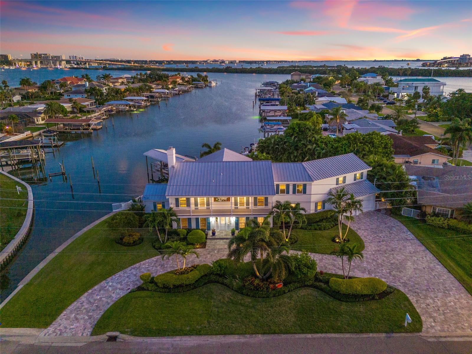 More than a home, this Island Estates retreat delivers the ultimate coastal lifestyle. Trade traffic for palm-lined bike rides to world-famous Clearwater Beach, or cast off from your private dock and cruise straight to dinner at your favorite waterfront restaurant. Set on an oversized lot with 179 feet of water frontage, the property feels like a private resort, complete with a sparkling PebbleTec pool and spa, a putting green for putting and chipping practice, and a dock outfitted with a covered boat lift plus a combo lift for personal watercraft. Inside, more than 5,000 square feet of living space gives everyone room and privacy. Meticulous updates throughout this five-bedroom, five-and-a-half-bath residence blend coastal luxury with everyday comfort. A light-filled foyer opens to voluminous living areas and a chef’s kitchen anchored by Viking appliances, marble countertops, and a classic subway-tile backsplash. The split-bedroom layout ensures seclusion for the primary suite, which features a spa-inspired bath and a balcony that is perfect for morning coffee above the water. Take the elevator to second floor where you have multiple en-suite bedrooms and a versatile 20×23-foot bonus room, ideal as a media lounge or game room. Whether you’re relaxing by the pool, practicing your short game, or launching kayaks from the dock, the backyard is designed for pure Florida fun. With effortless boating access, quick walks to the beach, and every island convenience just minutes away, this residence truly defines a waterfront playground. Come live where every day feels like a vacation.