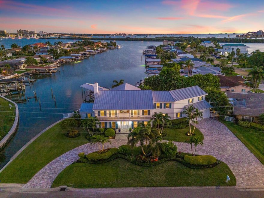 More than a home, this Island Estates retreat delivers the ultimate coastal lifestyle. Trade traffic for palm-lined bike rides to world-famous Clearwater Beach, or cast off from your private dock and cruise straight to dinner at your favorite waterfront restaurant. Set on an oversized lot with 179 feet of water frontage, the property feels like a private resort, complete with a sparkling PebbleTec pool and spa, a putting green for putting and chipping practice, and a dock outfitted with a covered boat lift plus a combo lift for personal watercraft.  Inside, more than 5,000 square feet of living space gives everyone room and privacy. Meticulous updates throughout this five-bedroom, five-and-a-half-bath residence blend coastal luxury with everyday comfort. A light-filled foyer opens to voluminous living areas and a chef’s kitchen anchored by Viking appliances, marble countertops, and a classic subway-tile backsplash. The split-bedroom layout ensures seclusion for the primary suite, which features a spa-inspired bath and a balcony that is perfect for morning coffee above the water.  Take the elevator to second floor where you have multiple en-suite bedrooms and a versatile 20×23-foot bonus room, ideal as a media lounge or game room. Whether you’re relaxing by the pool, practicing your short game, or launching kayaks from the dock, the backyard is designed for pure Florida fun.  With effortless boating access, quick walks to the beach, and every island convenience just minutes away, this residence truly defines a waterfront playground. Come live where every day feels like a vacation.