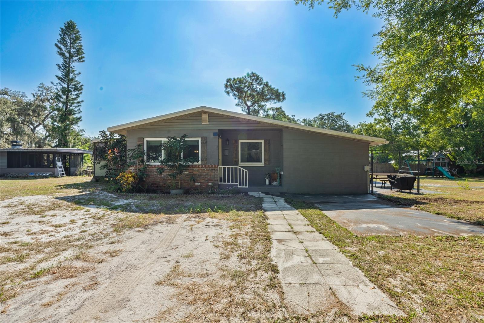 This concrete block home offers 3 bedrooms and 2 beautifully updated baths, featuring wood flooring throughout the living areas and upgraded flooring in the kitchen and baths. The remodeled kitchen, completed in 2019, showcases modern finishes and butcher block-style counters. A spacious family room flows to a ground-level concrete patio overlooking the fully fenced 1.58-acre property. Enjoy a screened porch, Kentico water filtration system, and abundant storage options. The property includes a concrete block cookhouse with electric, sink, and brick fire pit, an attached 8x12 storage area, two additional large sheds, and ample space for equipment, RVs, or large vehicle parking. A private RV hookup with separate septic, water, and electric is already in place. Recent upgrades include a new roof (2023), new A/C (2024), and shaded outside paver stones area with a potting bench and rain barrel. Located at the end of a private road with a perimeter tree buffer, this home offers exceptional privacy and versatile outdoor living.
